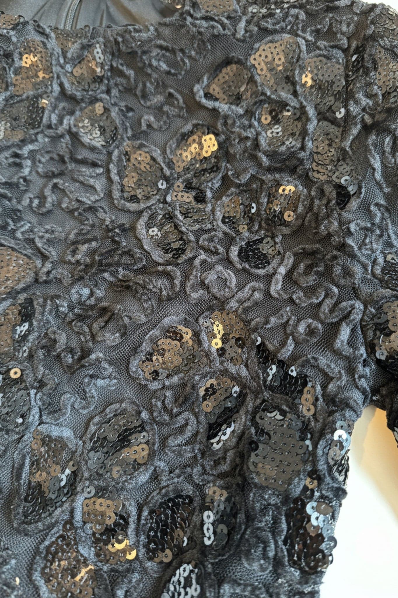 Tessuto delicato del pizzo nero e brillantezza delle paillettes sulle maniche lunghe di questo abito, ideale per occasioni...