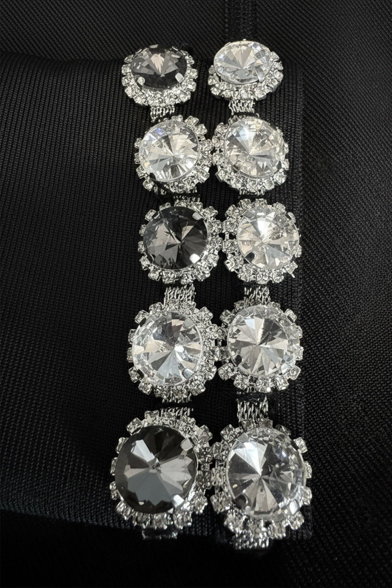 Dettagli in primo piano di un abito nero corto a maniche lunghe, con un elegante collo gioiello impreziosito da cristalli...