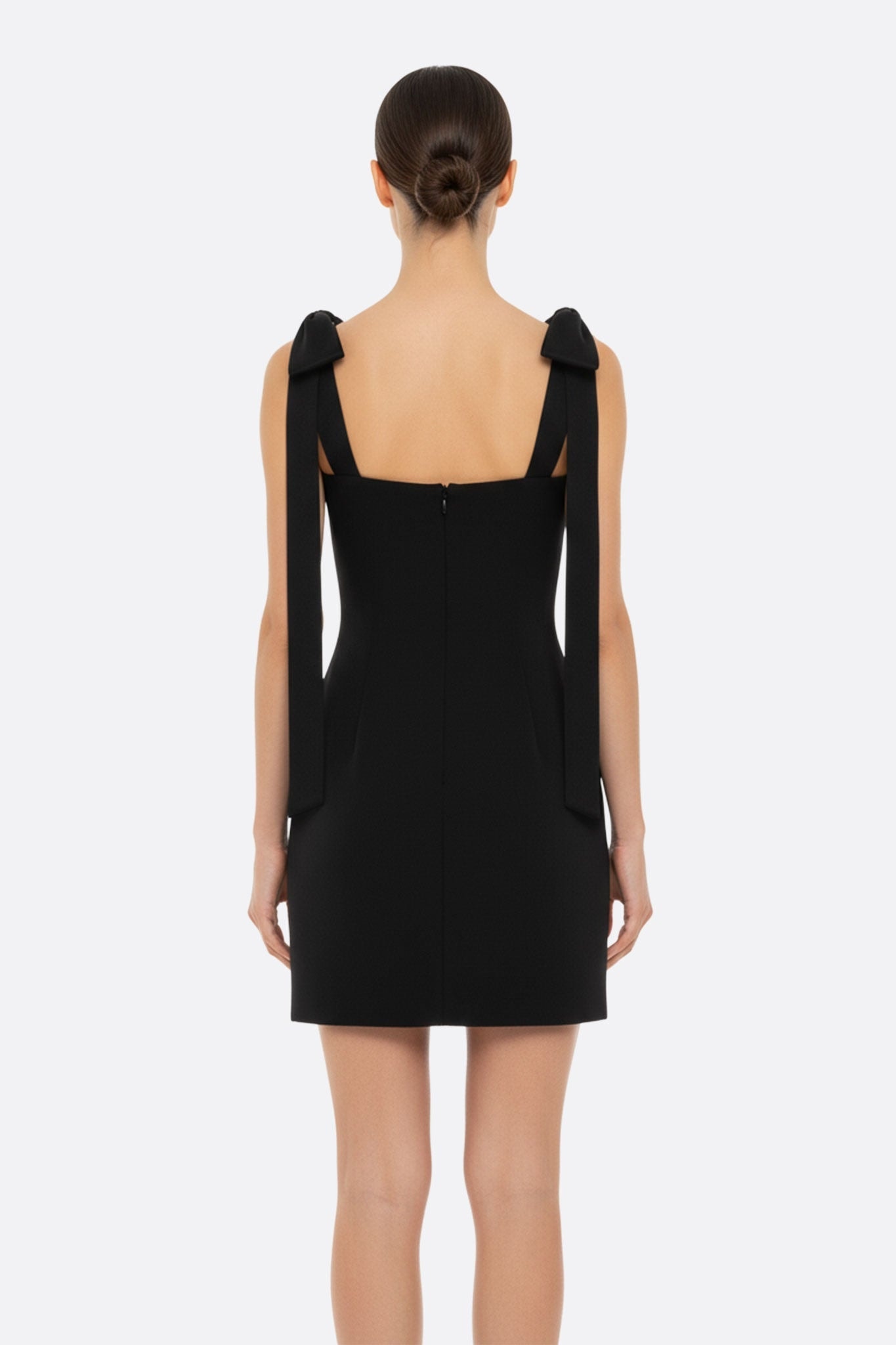 Robe noire courte au style épuré, ornée de perles et de nœuds charmants, idéale pour des occasions élégantes.