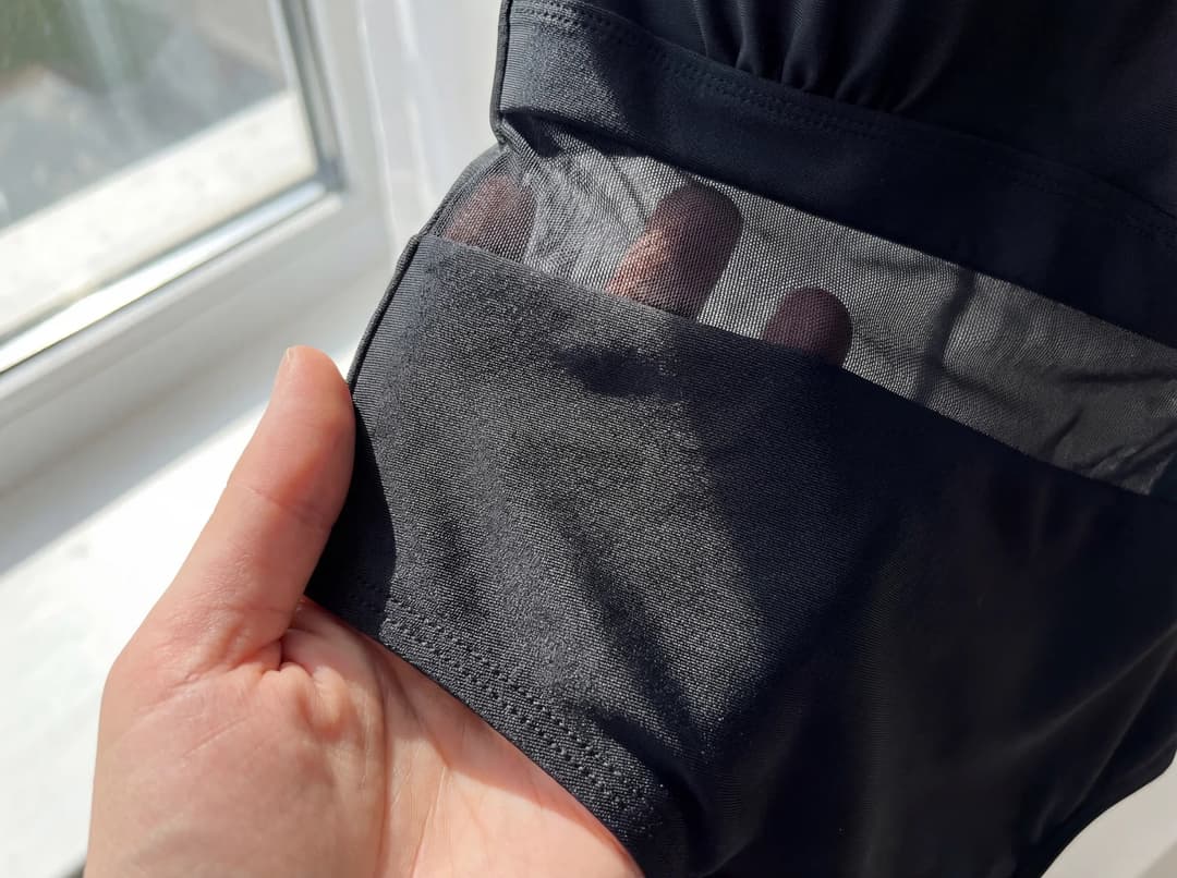 Femme examinant au toucher le tissu d’un maillot de bain à la lumière naturelle.