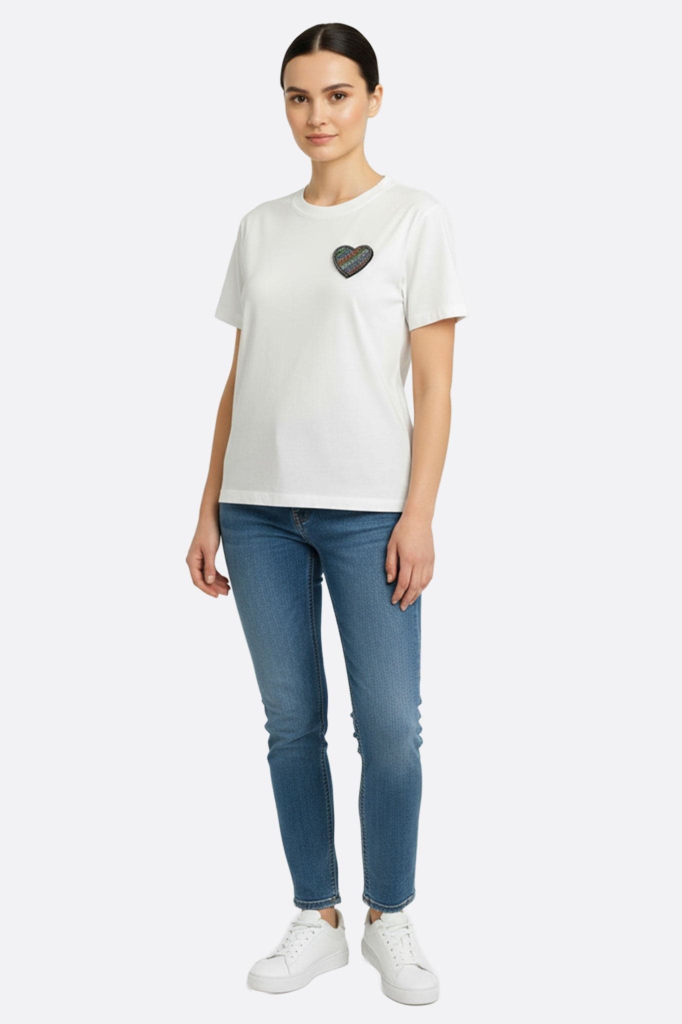 Close-up of the delicate heart embroidery on a chic white short-sleeved T-shirt, ideal for a casual evening out.