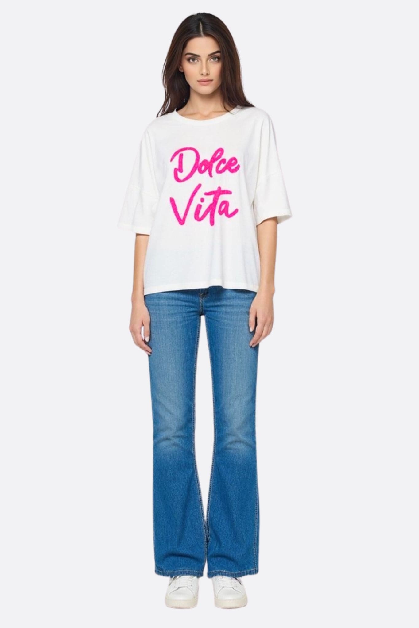 Nahaufnahme des weißen T-Shirts mit fallenden Schultern, die den fuchsiarosa Bouclette-Schriftzug 'Dolce Vita' hervorhebt.