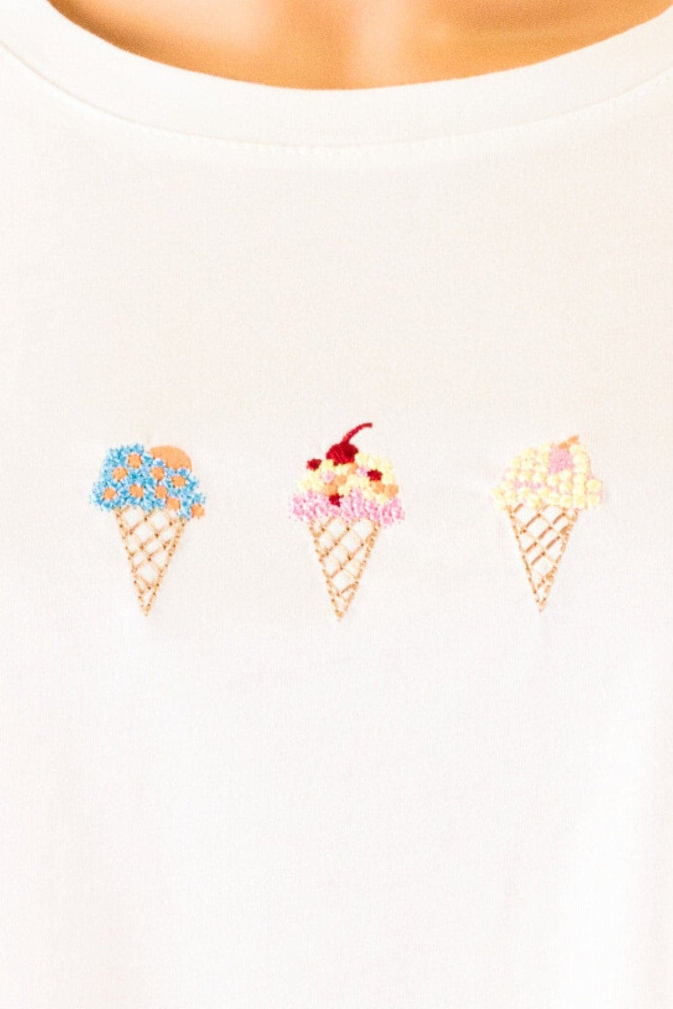 Detail der weichen Textur und feinen Stickerei des weißen Oversize-Gelato-T-Shirts, perfekt für einen täglichen Stil...