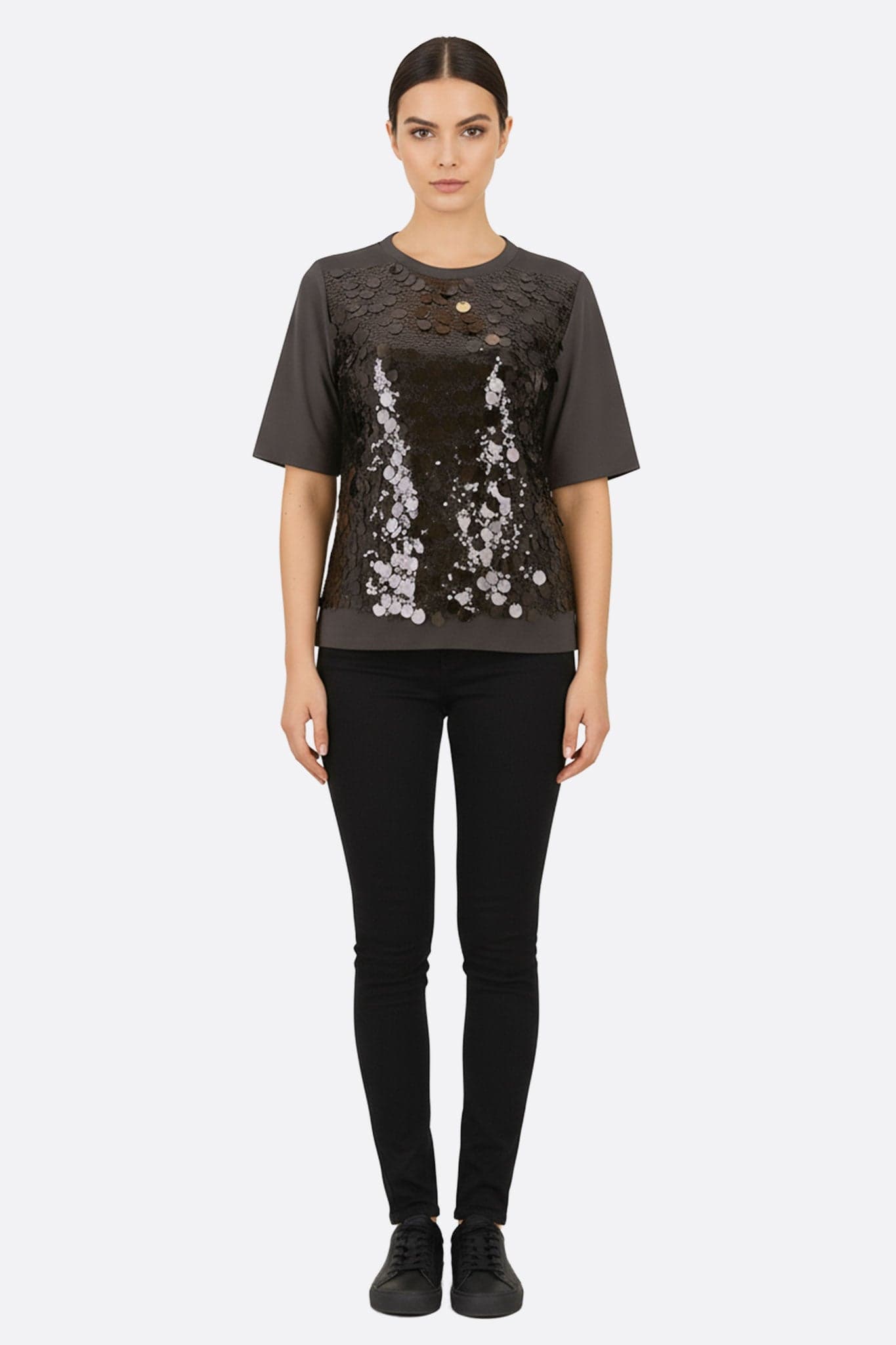 Vergrößertes Detail des schwarzen Baumwoll-T-Shirts, veredelt mit glänzenden Pailletten, perfekt für einen raffinierten Alltagslook.