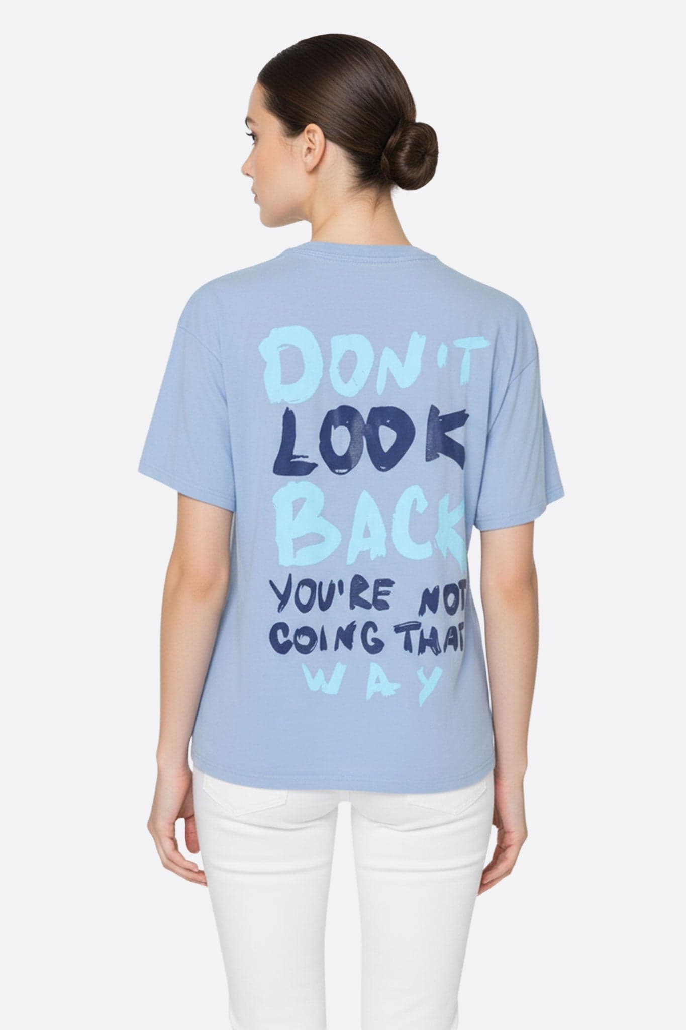 Primo piano sulla texture di una t-shirt azzurro cielo dal taglio ampio, con il messaggio motivante "Don't look back", ideale per...