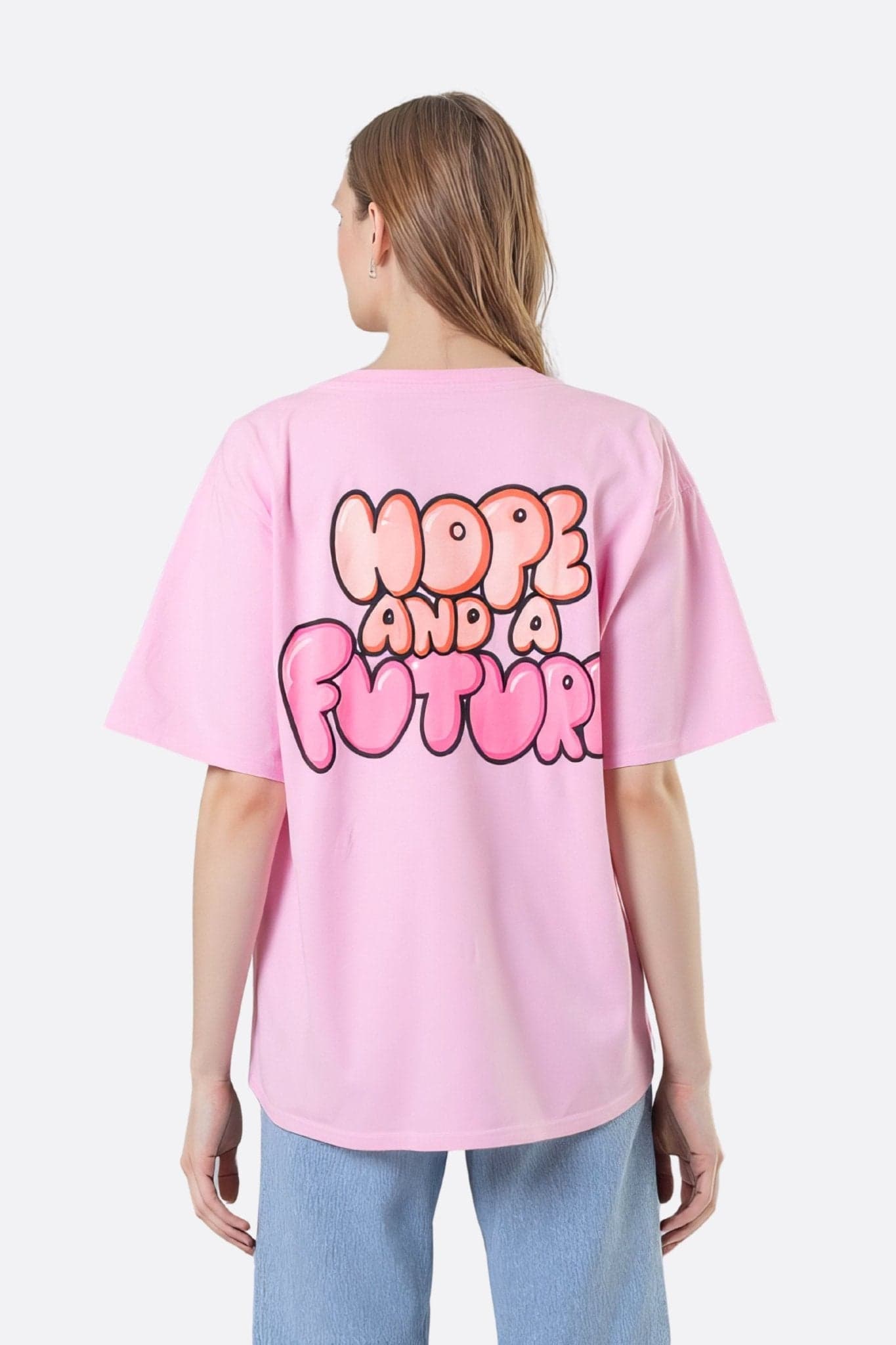 Dettaglio della t-shirt oversize in cotone rosa pastello, che mette in evidenza la sua scritta ispiratrice, perfetta per un look...