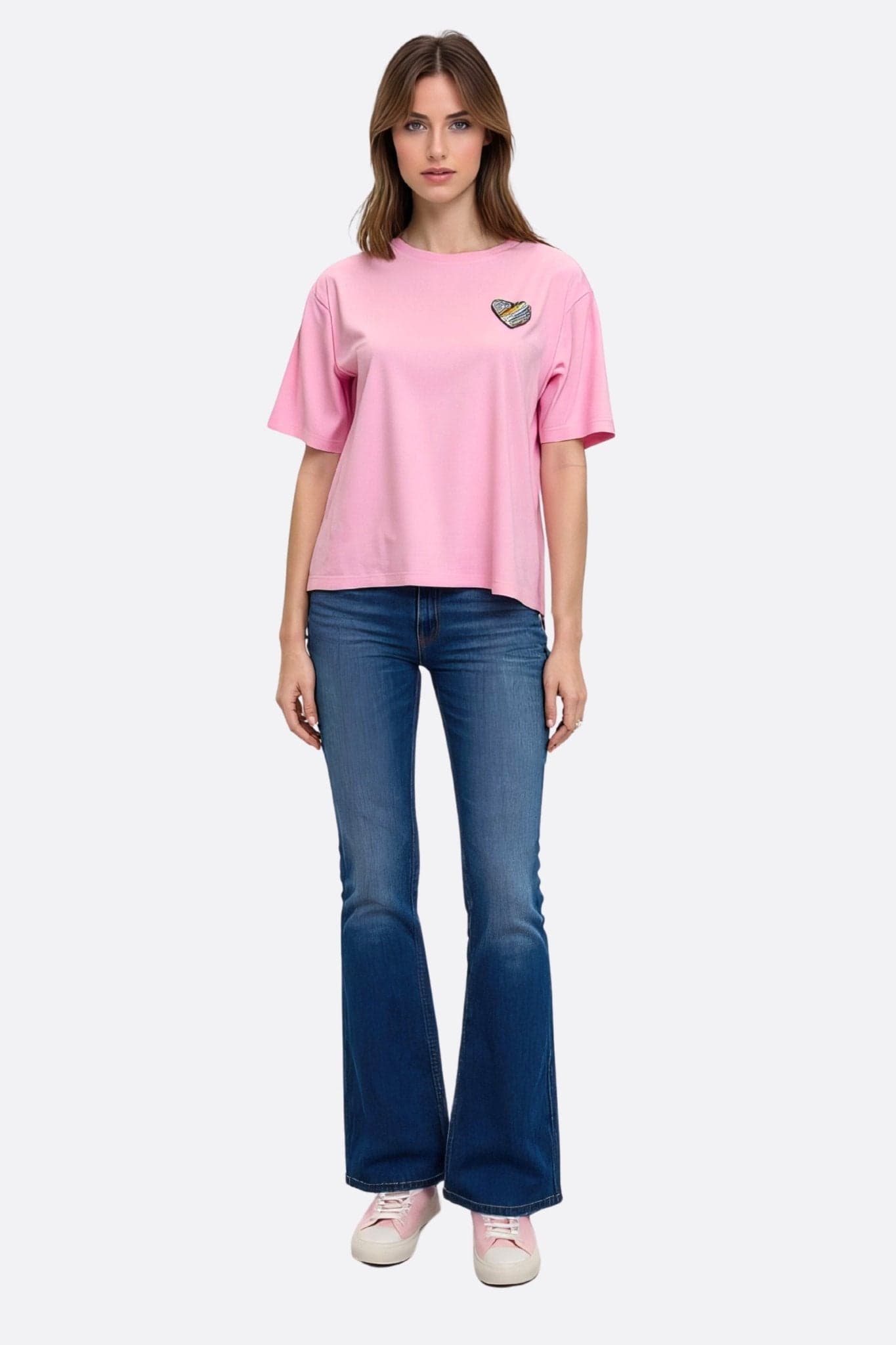 Zoom sur la broderie en cœur d'un t-shirt rose à manches courtes, un incontournable pour une allure décontractée et élégante.