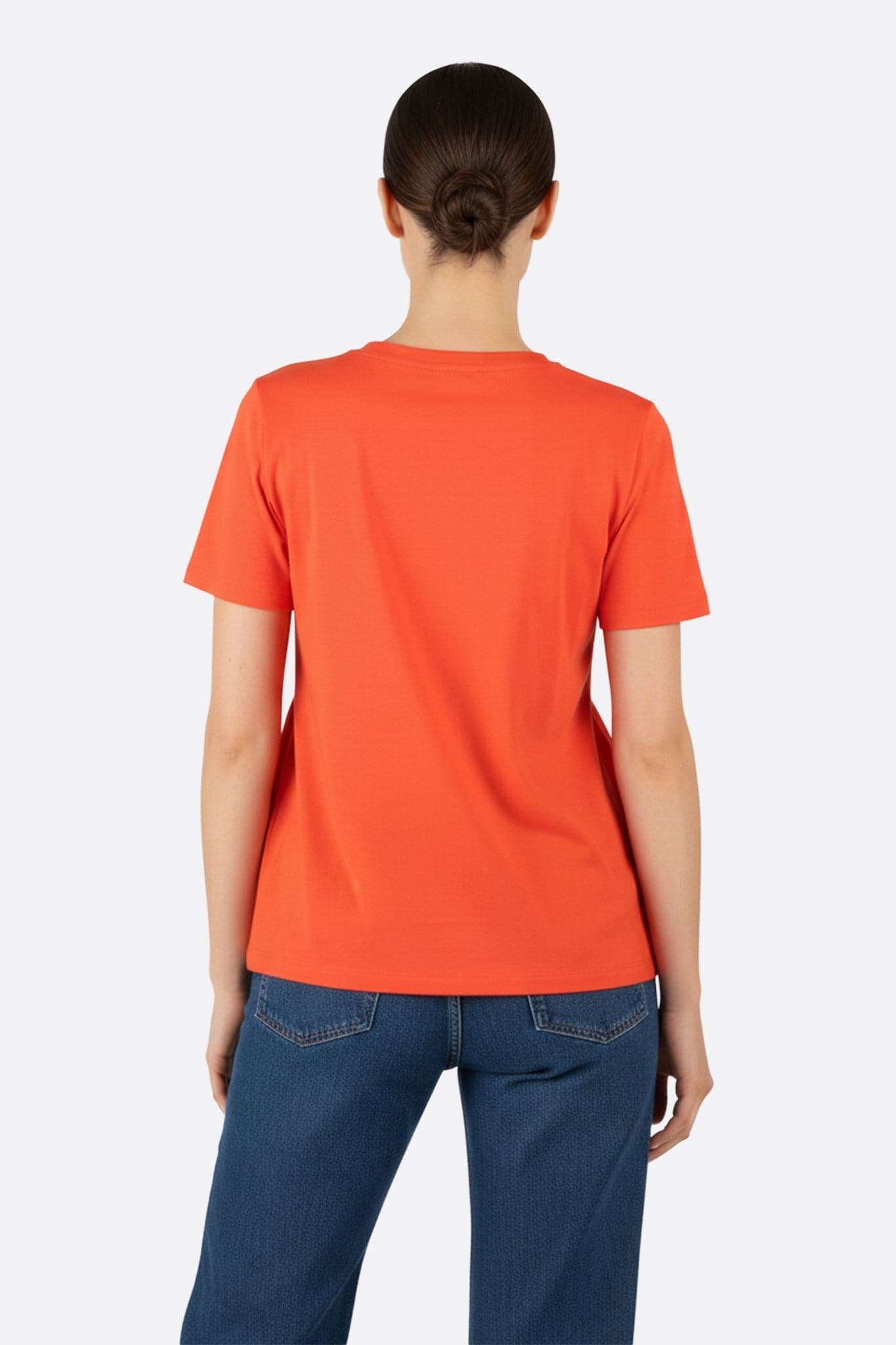 Elegant ruching on the back of a coral oversized t-shirt, chic model for a casual and stylish look on a night out.