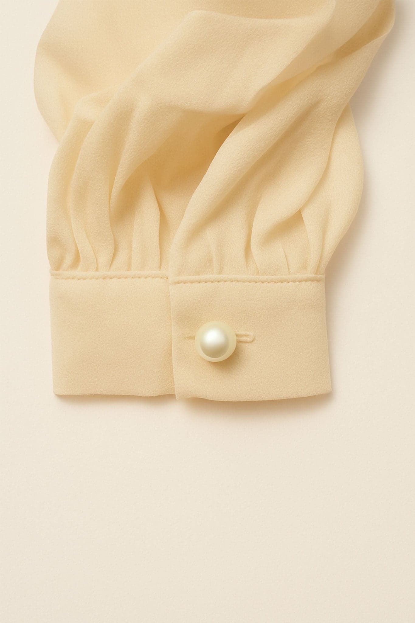 Top féminin asymétrique en blanc écru avec drapé et fleur sculptée, un choix raffiné pour des occasions spéciales.