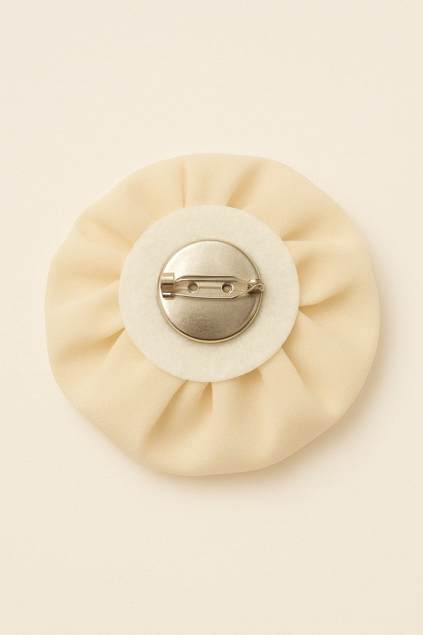 Détail artistique d'un haut asymétrique en blanc écru, drapé et orné d'une fleur sculptée, essentiel pour un look raffiné.