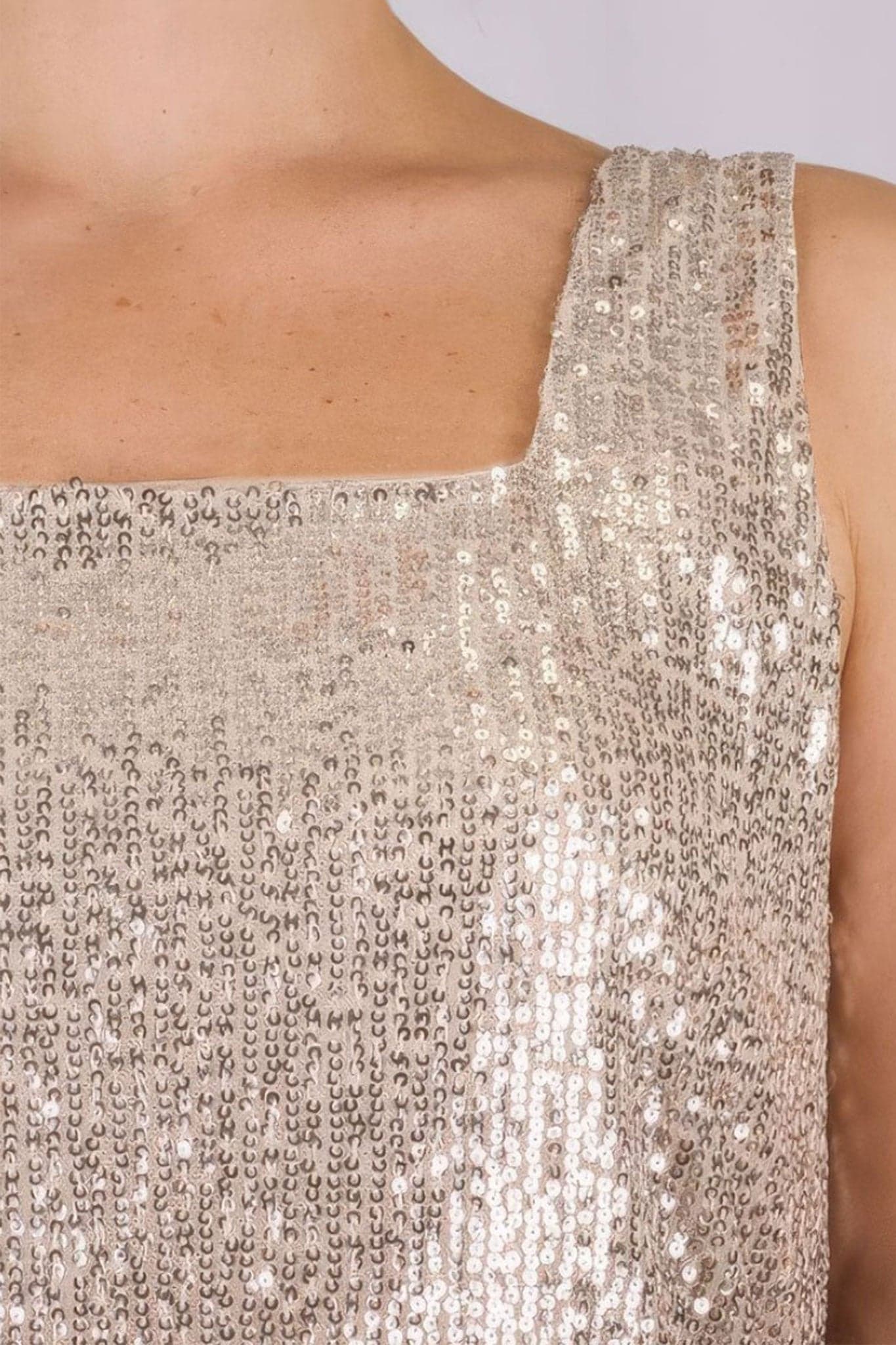 Detail of the beige top with iridescent sequins, showcasing its fluid texture and elegant charm for glamorous evenings.
