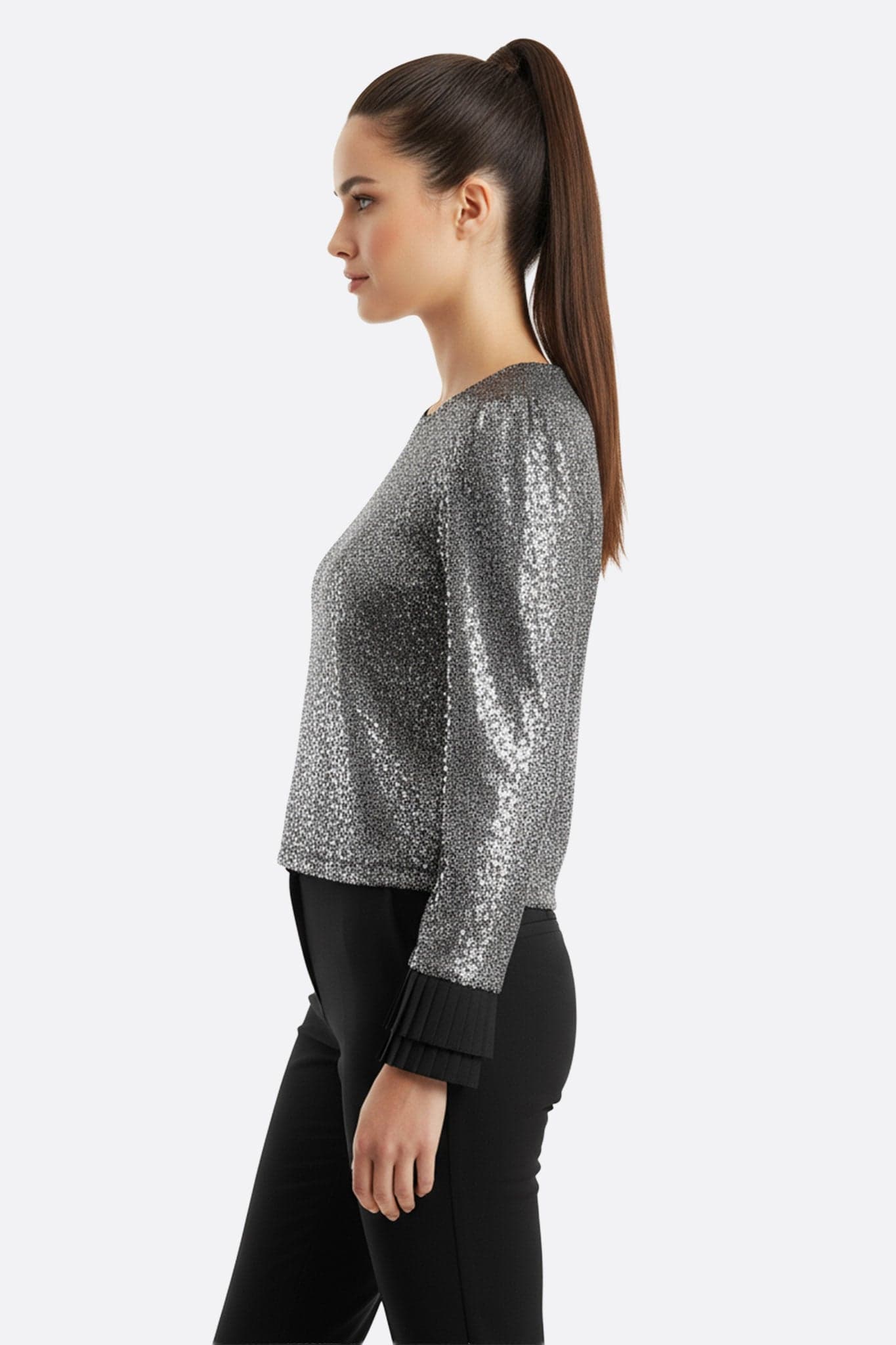 Détail élégant des poignets plissés du top noir, sublimé par des sequins argent, idéal pour une occasion chic et festive.