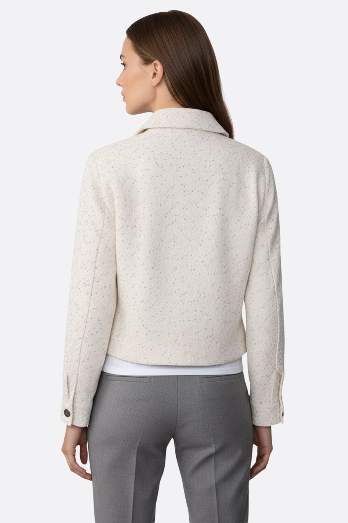 Détails d'une veste courte en tweed blanc ornée de sequins, une pièce élégante pour sublimer une tenue de fête.