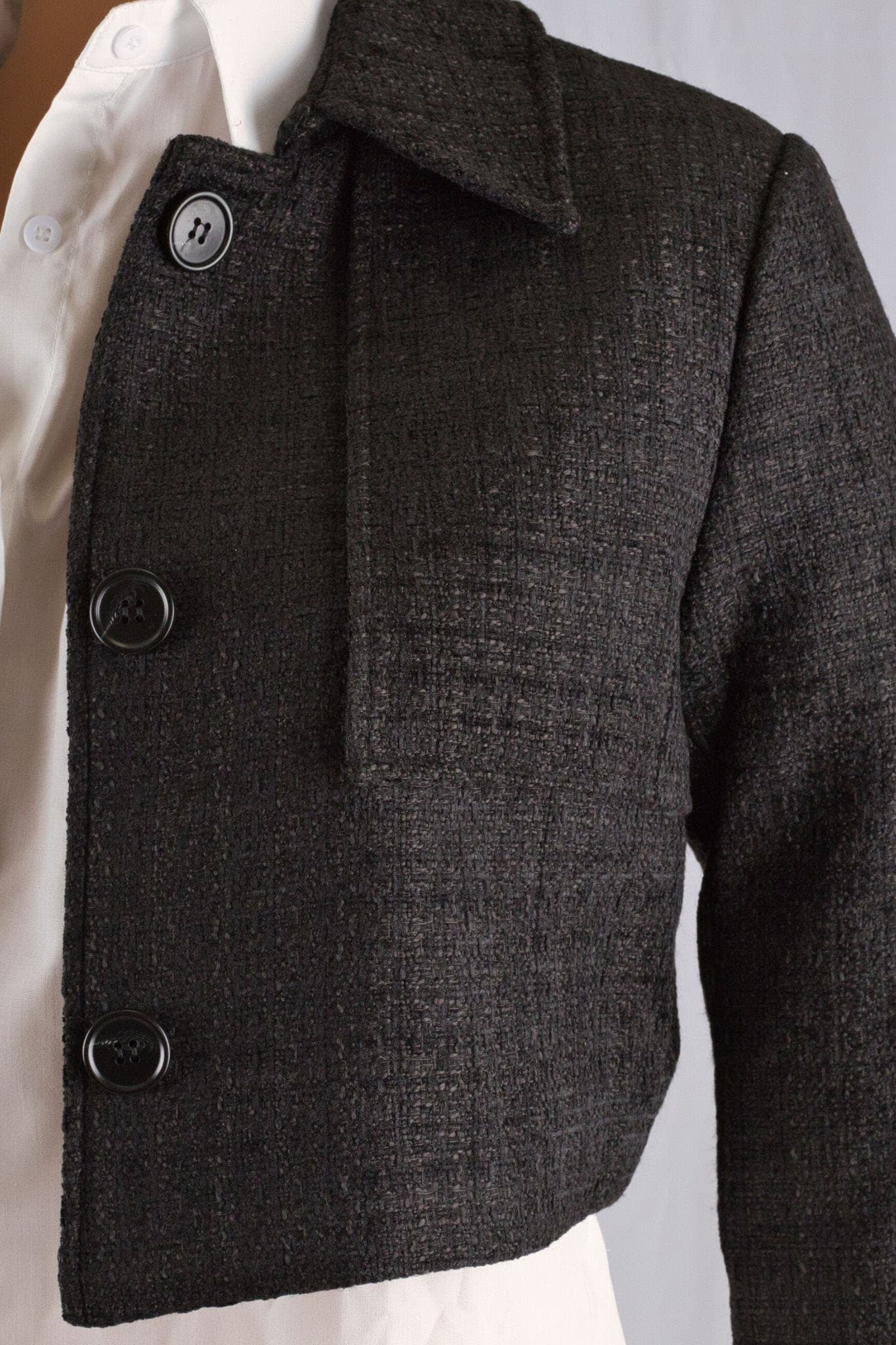 Black tweed jacket in cropped style, with satin lining, perfect for a slim and elegant silhouette.