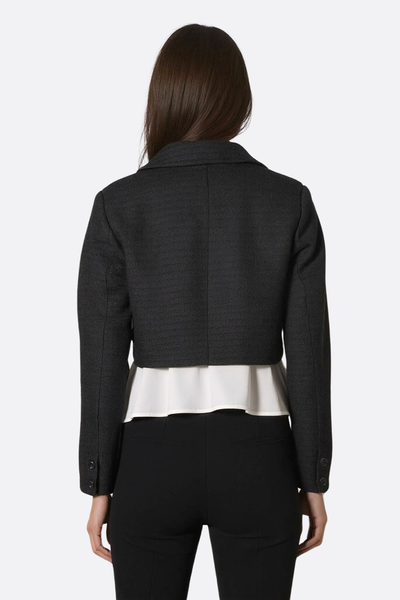 Close-up of the short black tweed jacket, highlighting its unique texture and satin lining for a chic allure.
