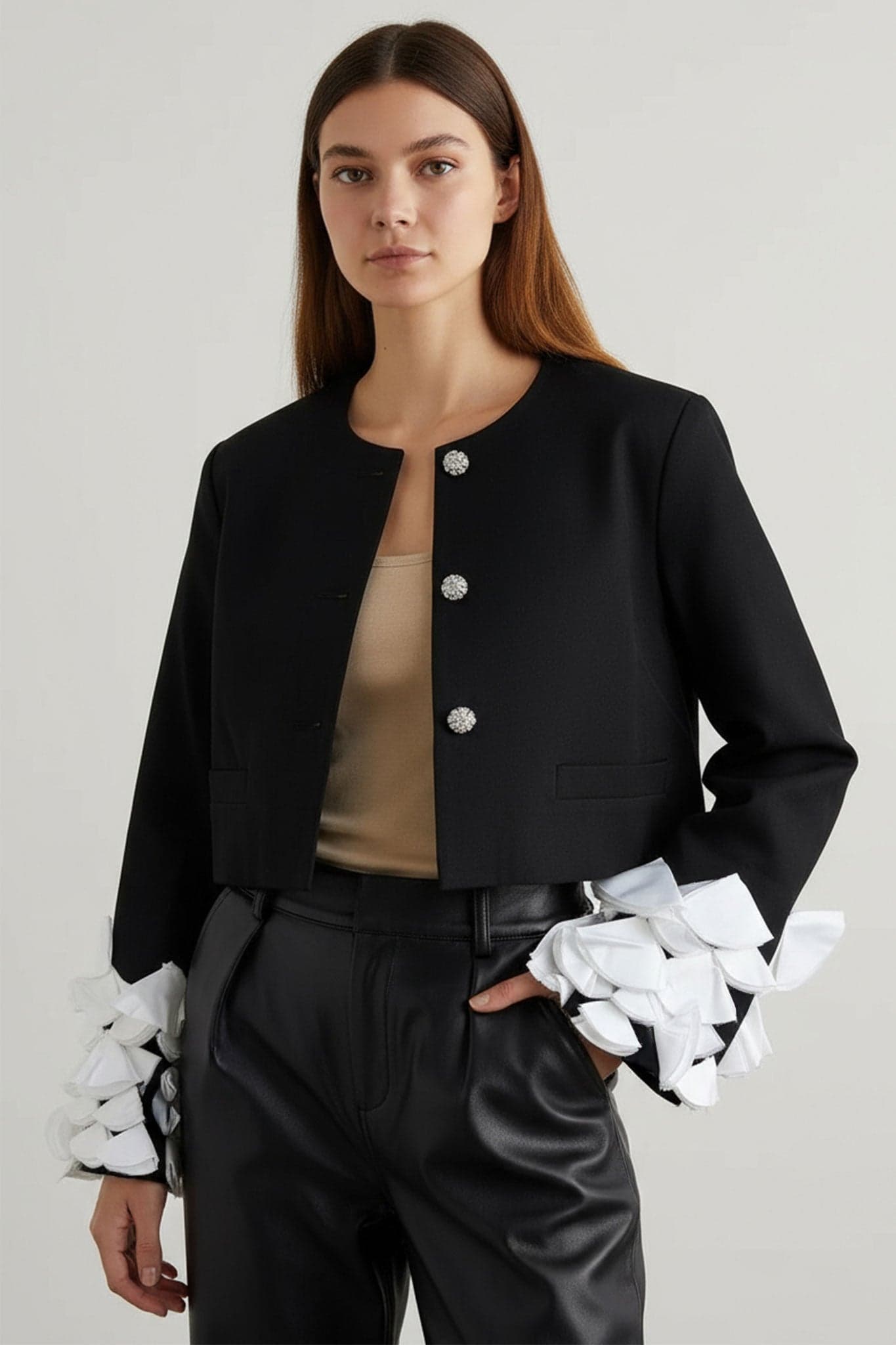 Exquisites Detail der weißen Federn auf den Blütenblattärmeln der schwarzen Jacke, verleiht einem raffinierten Look einen charmanten Akzent.