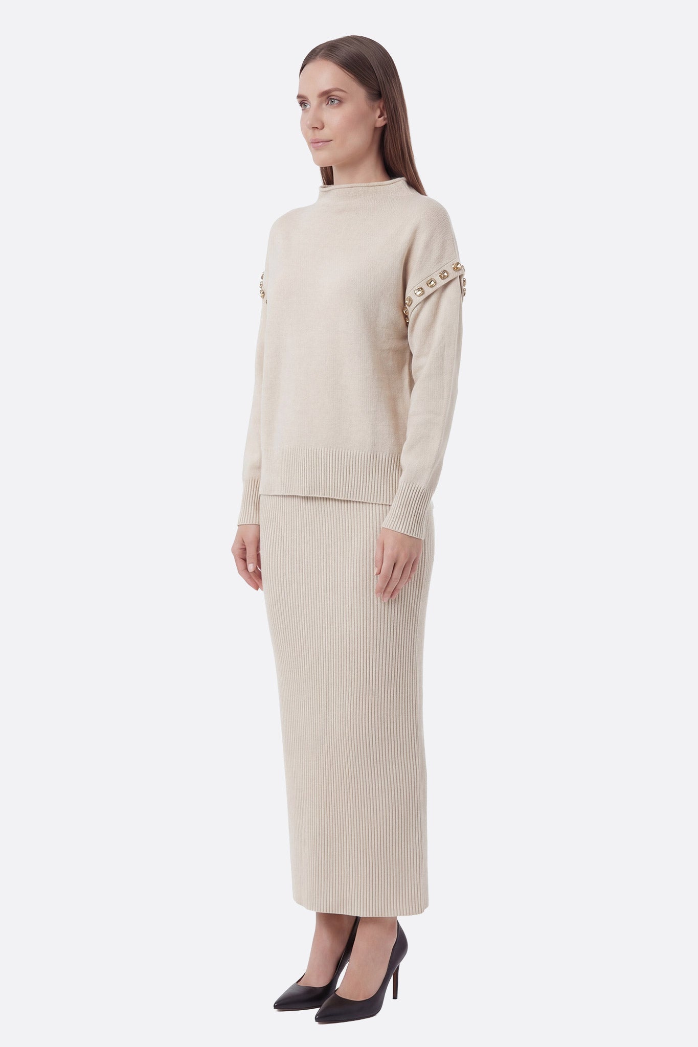 
Détails de la jupe longue en maille écru assortie à un pull doux, idéal pour un look élégant en journée ou soirée.



