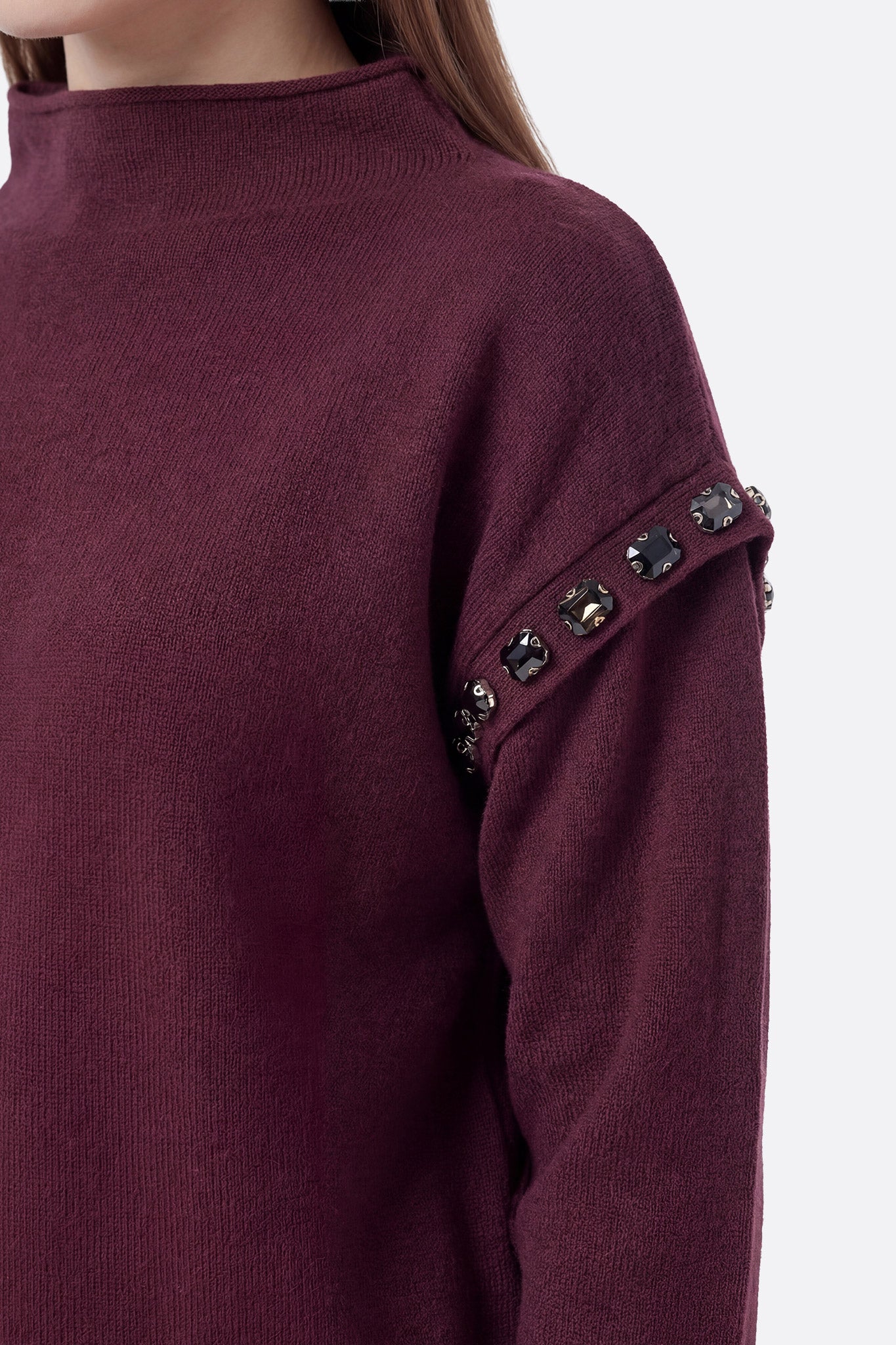 
Détail de l'ensemble bordeaux en maille avec jupe longue et pull à col montant, idéal pour une soirée raffinée.



