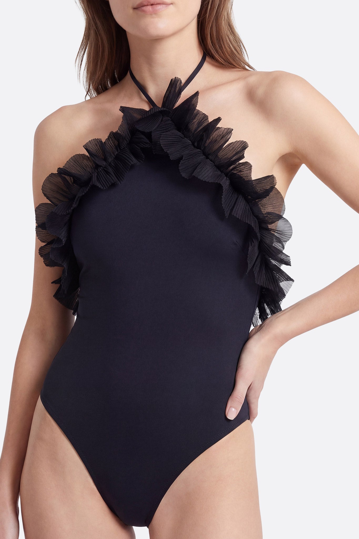 
Zoom sur le décolleté d'un maillot de bain une pièce noir à volants, un choix raffiné pour des moments de détente au soleil.



