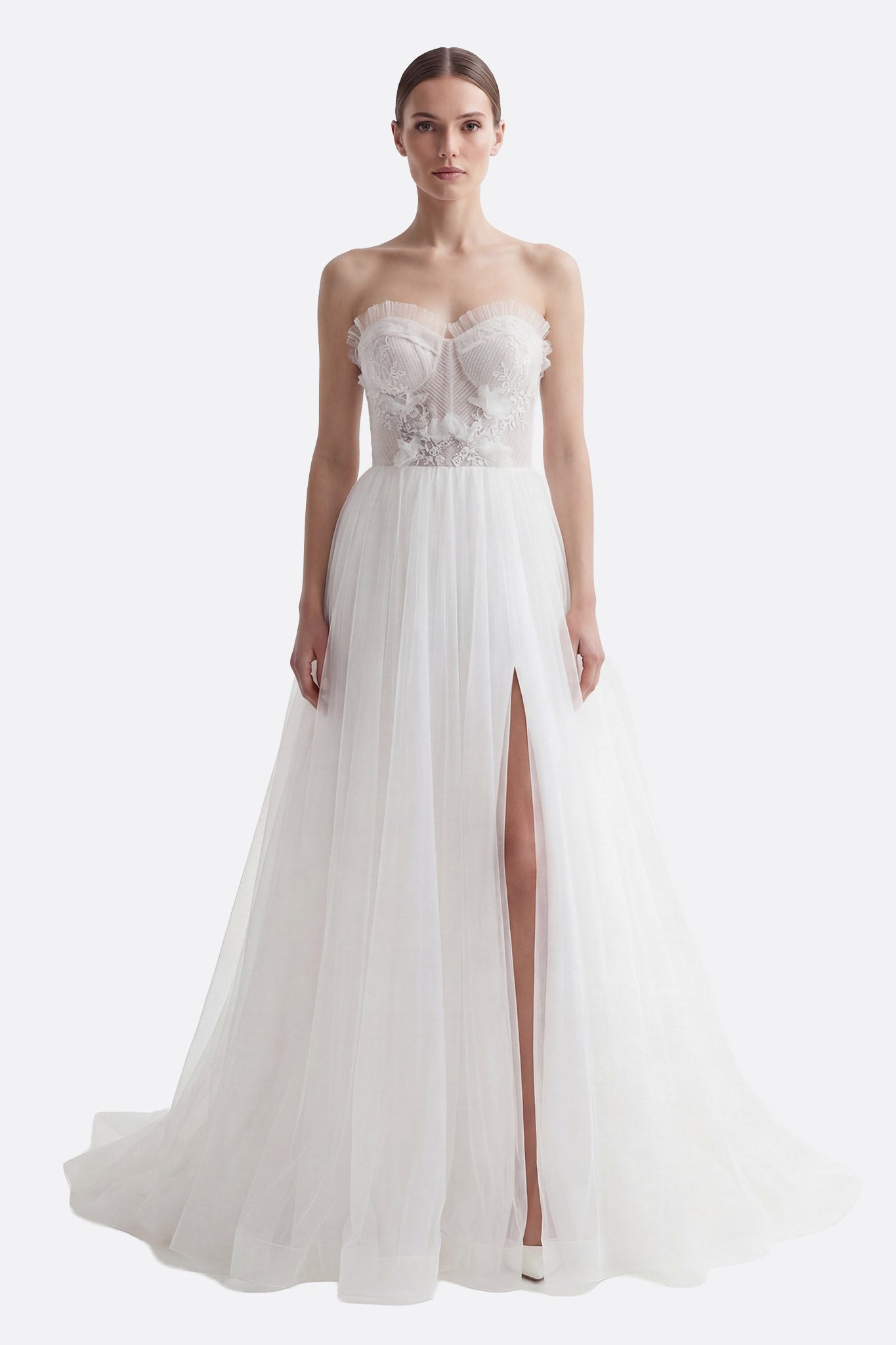 
Détail de la jupe fendue de la robe de mariée en tulle, mettant en valeur le bustier brodé et la cape amovible.



