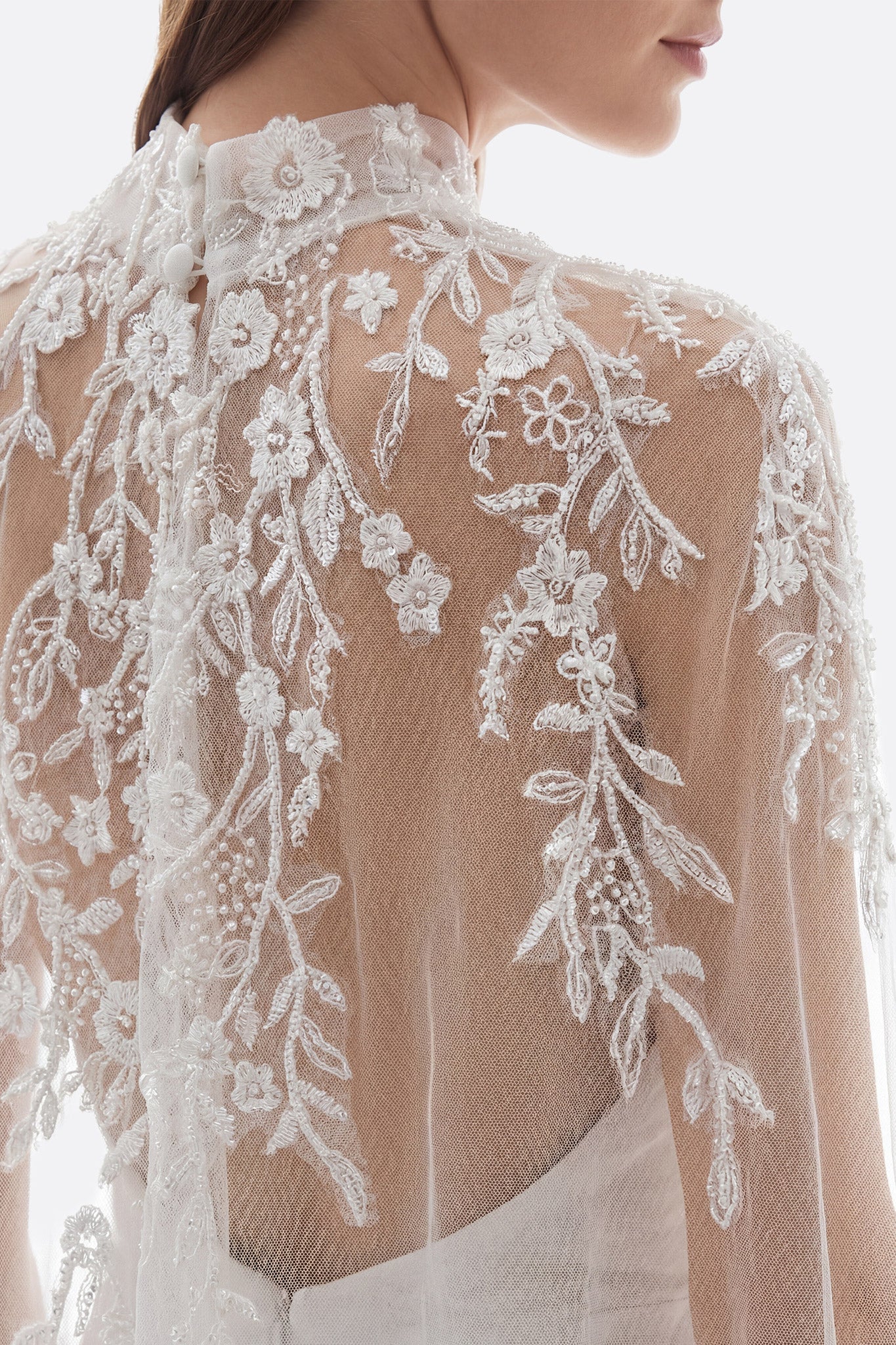 Stunning strapless tulle wedding gown with intricately embroidered corset, sultry thigh-high slit, and a chic removable cape.