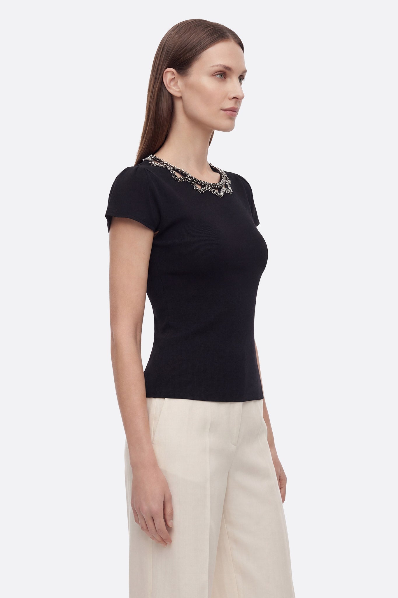 Vue rapprochée du T-shirt noir en maille stretch, mettant en valeur le col bijou raffiné pour une touche chic.