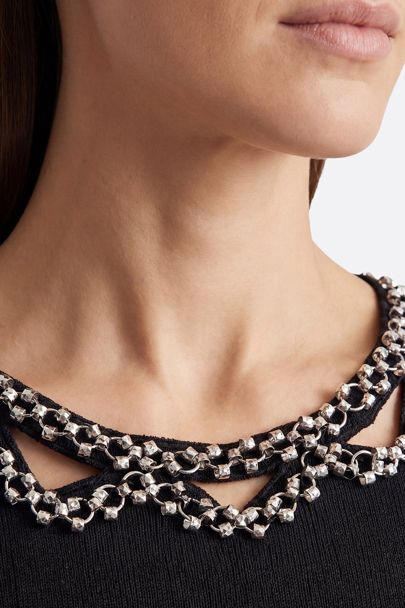 
Angle différent du T-shirt noir ajusté en maille stretch, accentuant la coupe sculptante et l'élégance du col bijou.



