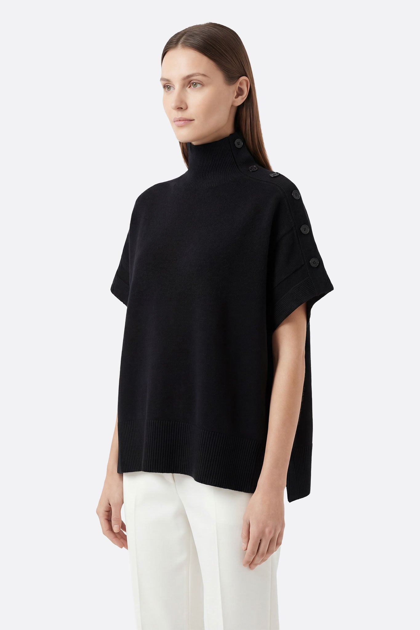 
Zoom sur le col montant boutonné du pull noir oversize, révélant la texture en maille douce et un style idéal pour les...



