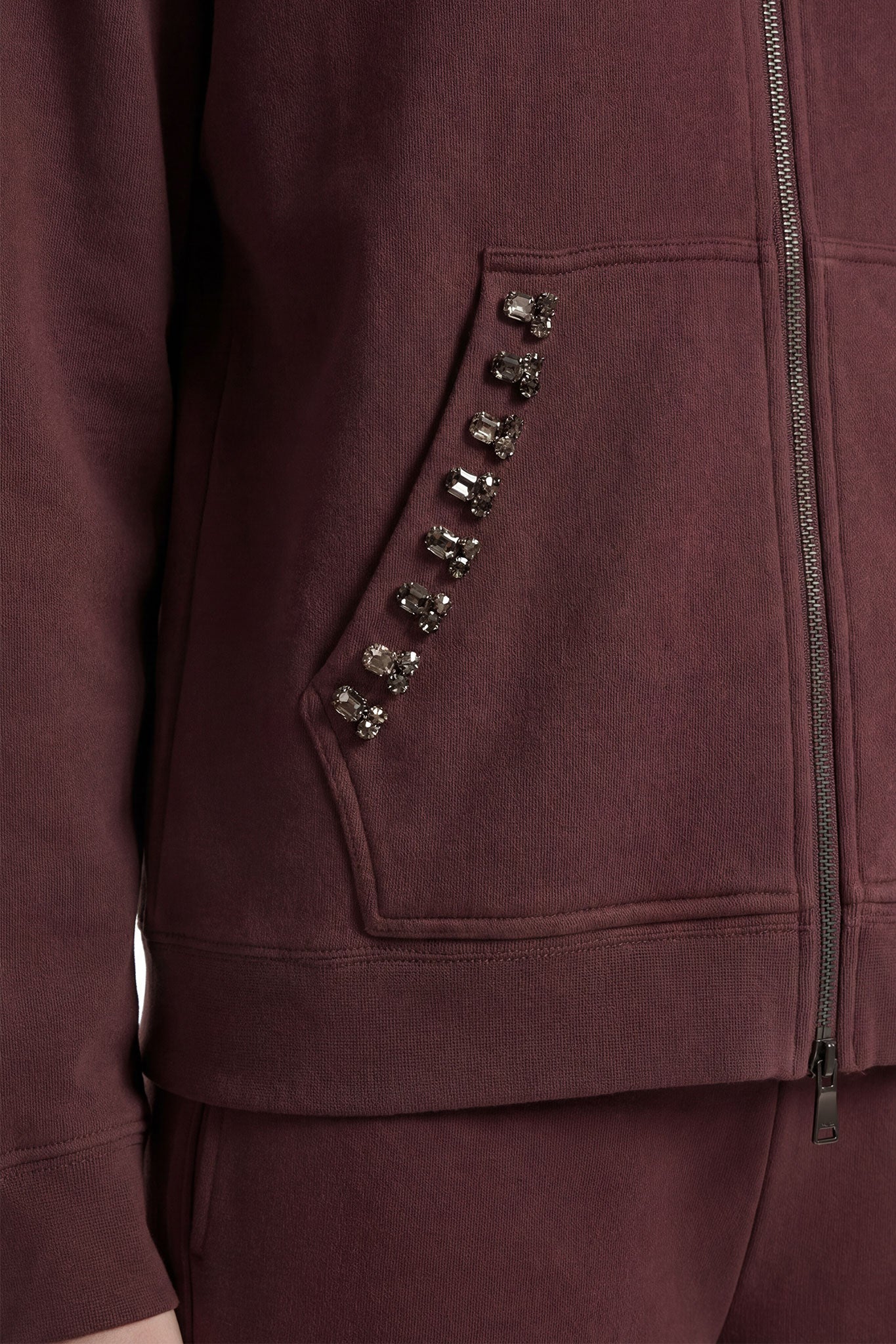 
Zoom sur le survêtement marron, mettant en valeur les cristaux facettés pour une allure chic en toute occasion.



