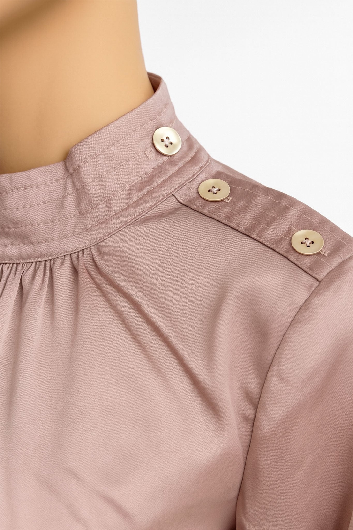 
Col montant froncé de la blouse en satin rose poudrée, mettant en avant son élégance raffinée pour des occasions spéciales.




