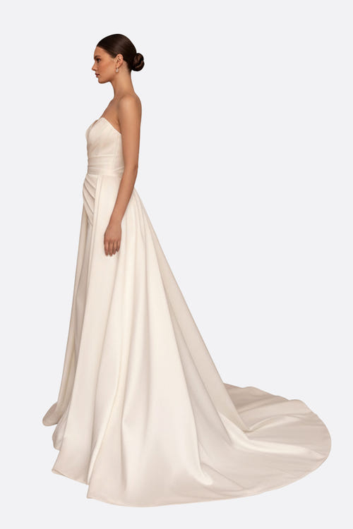 
Détail d'une robe de mariée blanche bustier, mettant en avant la texture satinée et le mouvement élégant de la traîne.



