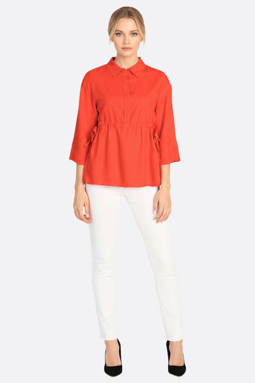 
Zoom sur la blouse fluide en lin rouge corail, mettant en valeur sa texture délicate et ses liens ajustables, chic pour...



