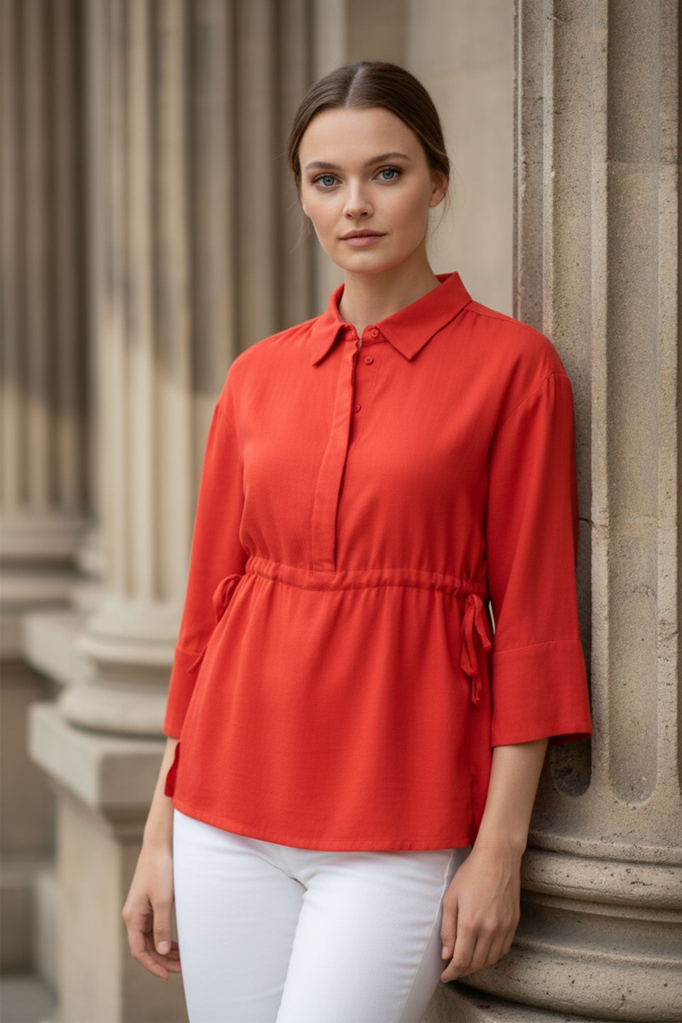 Dettaglio della blusa in lino rosso corallo con texture leggera e lacci regolabili, ideale per un look estivo elegante e...