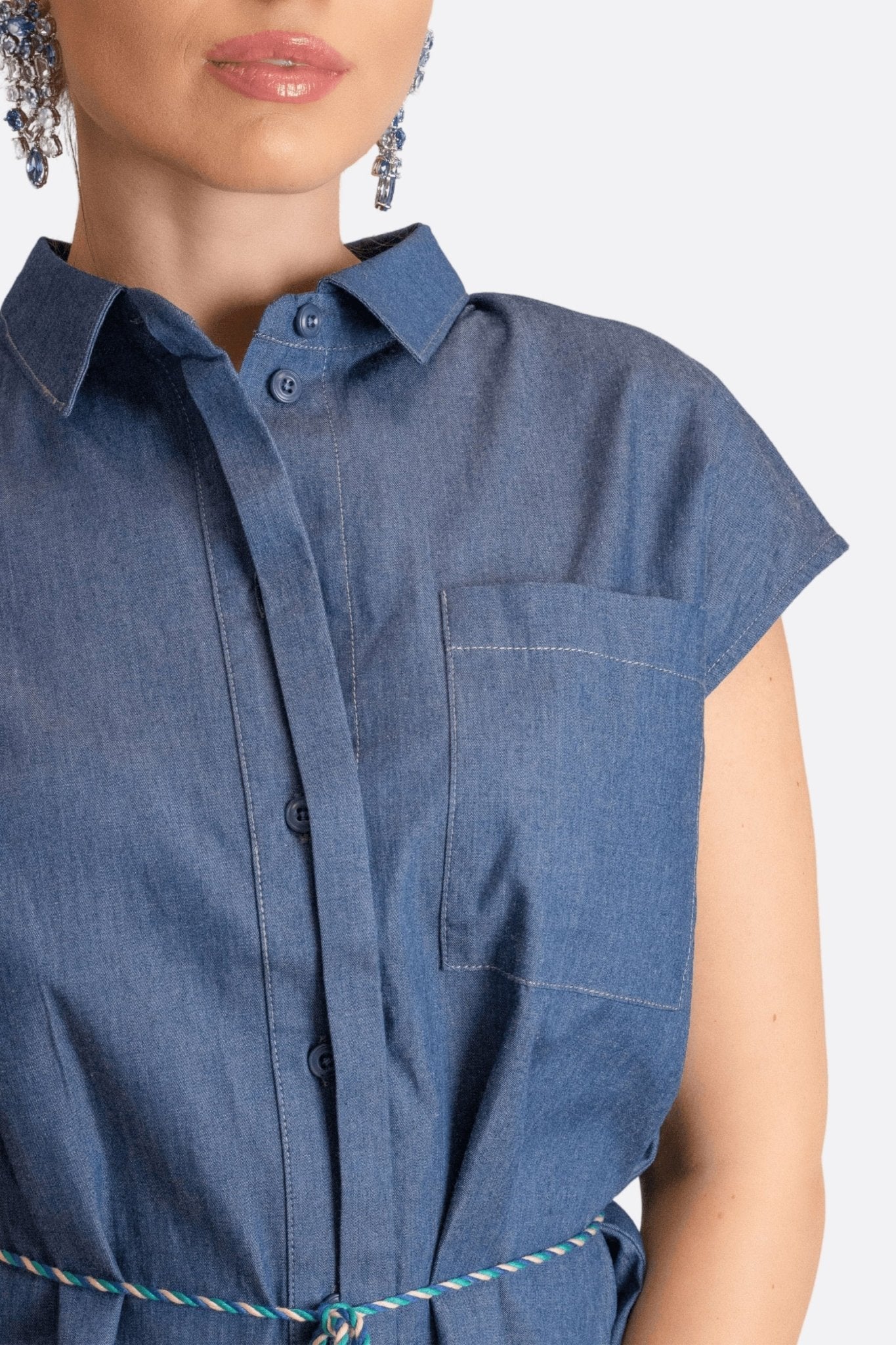 Blusa in denim blu senza maniche, vista alternativa che evidenzia il colletto classico e la tasca per uno stile casual e...