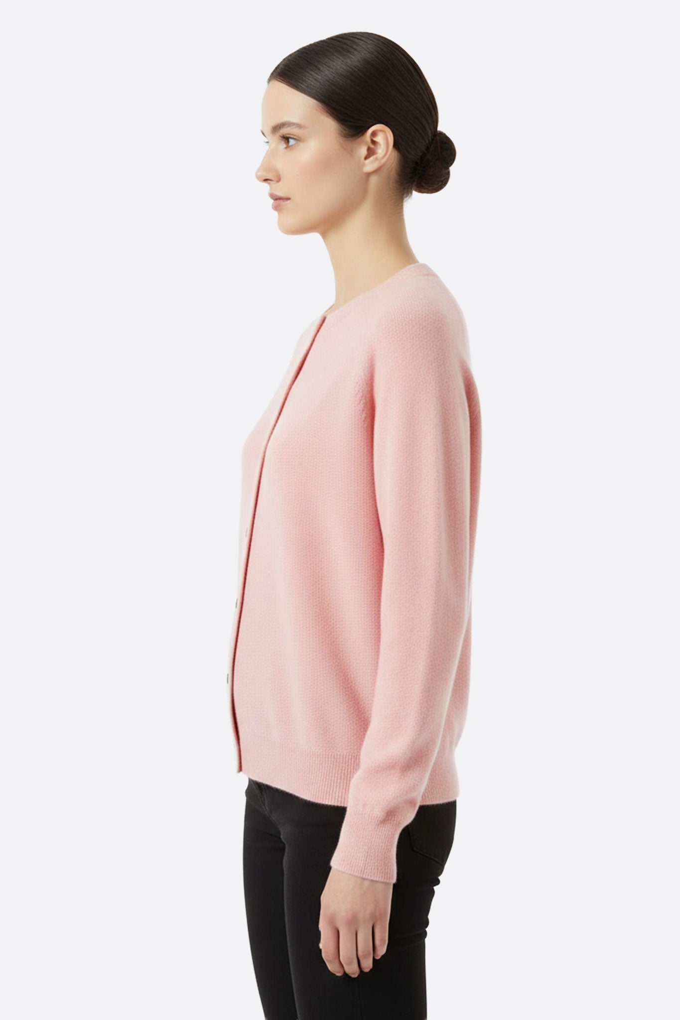 Zoom sur le cardigan en laine rose poudré, mettant en avant la texture délicate des mailles et l'élégance de ses manches...