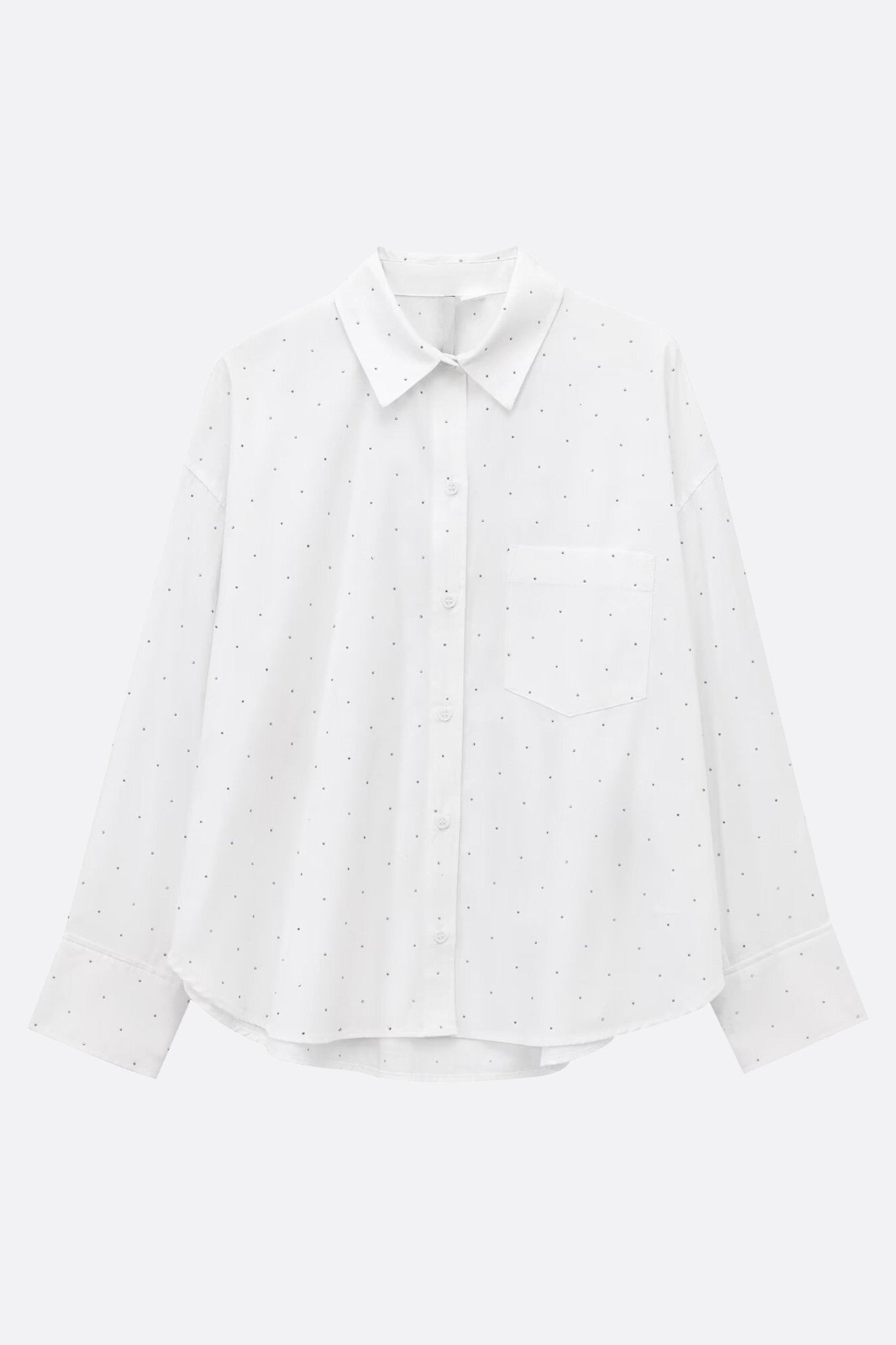 
Angle détaillé sur la chemise blanche ample avec strass, un choix chic pour une élégance moderne au bureau.



