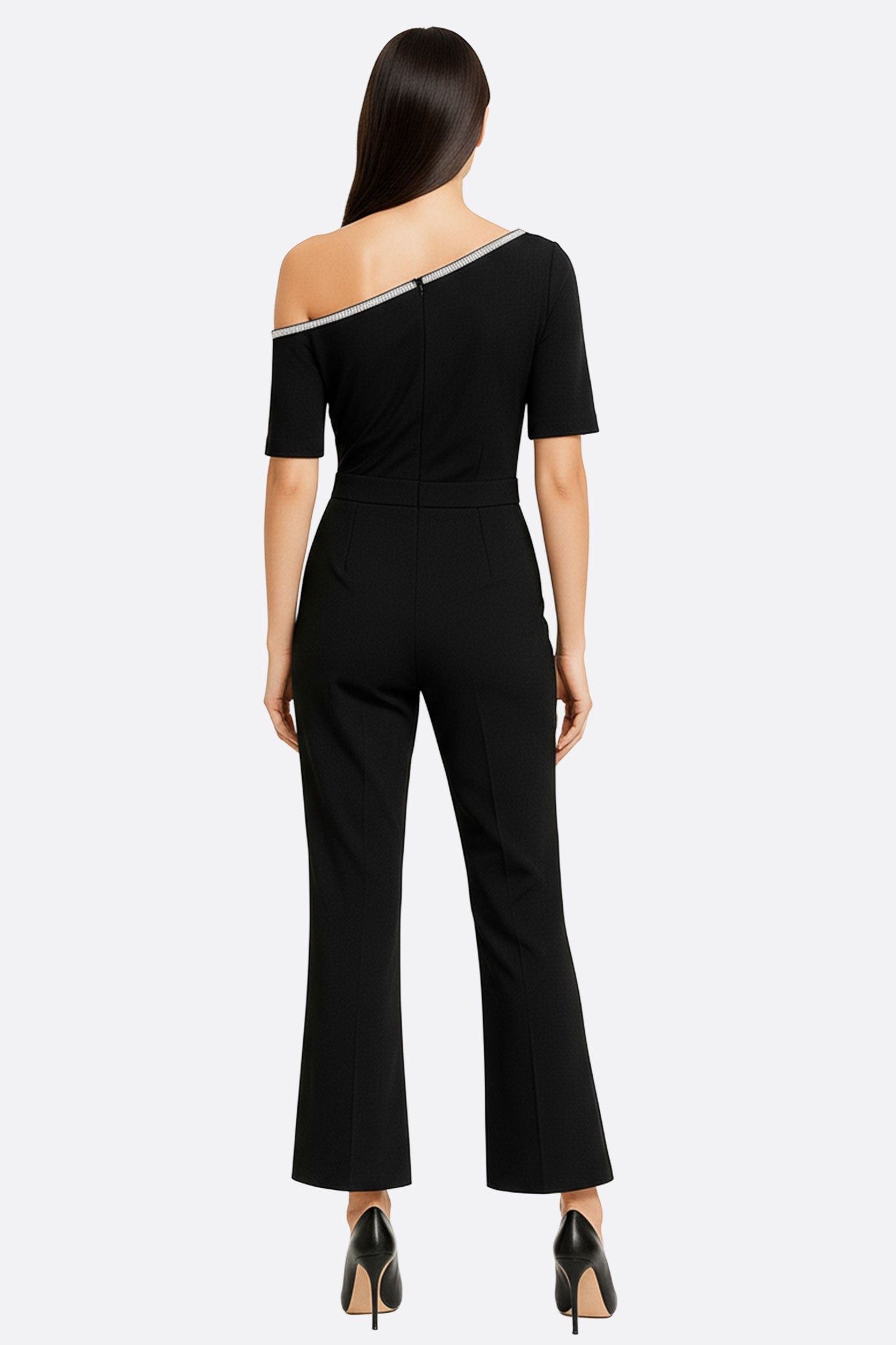 Zoom sur la combinaison noire asymétrique, mettant en lumière son élégance moderne et sa coupe unique pour un style raffiné.