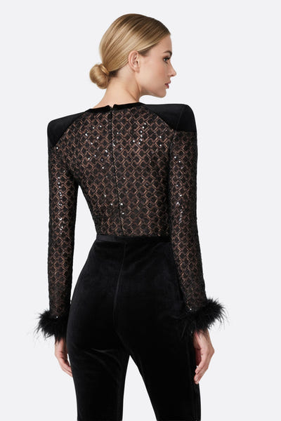 
Zoom sur la combinaison noire en velours et tulle, décorée de sequins scintillants pour un style raffiné et moderne.



