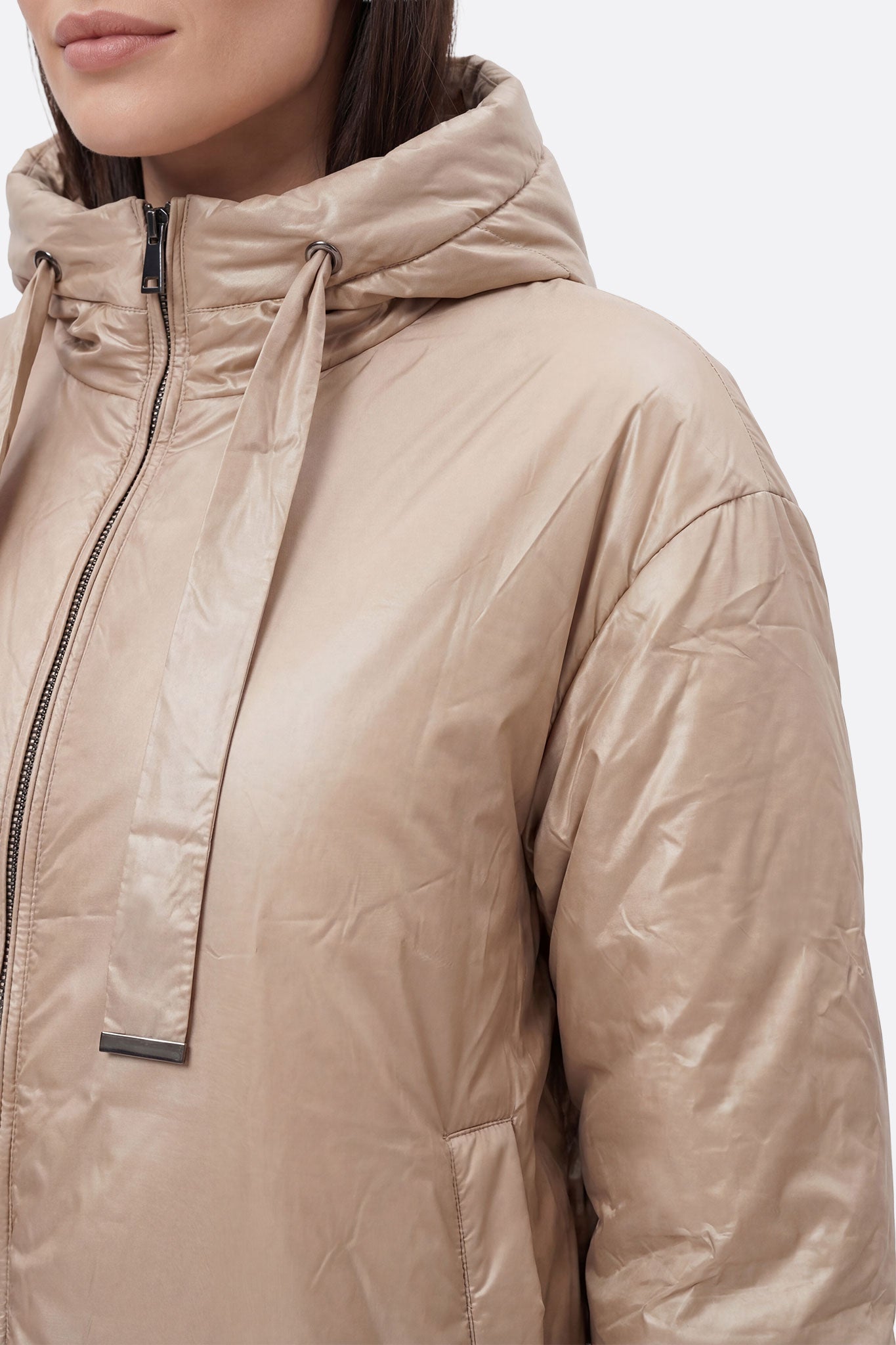 
Doudoune beige en satin, vue latérale sur la capuche et les liens ajustables, parfaite pour l'hiver chic et élégant.



