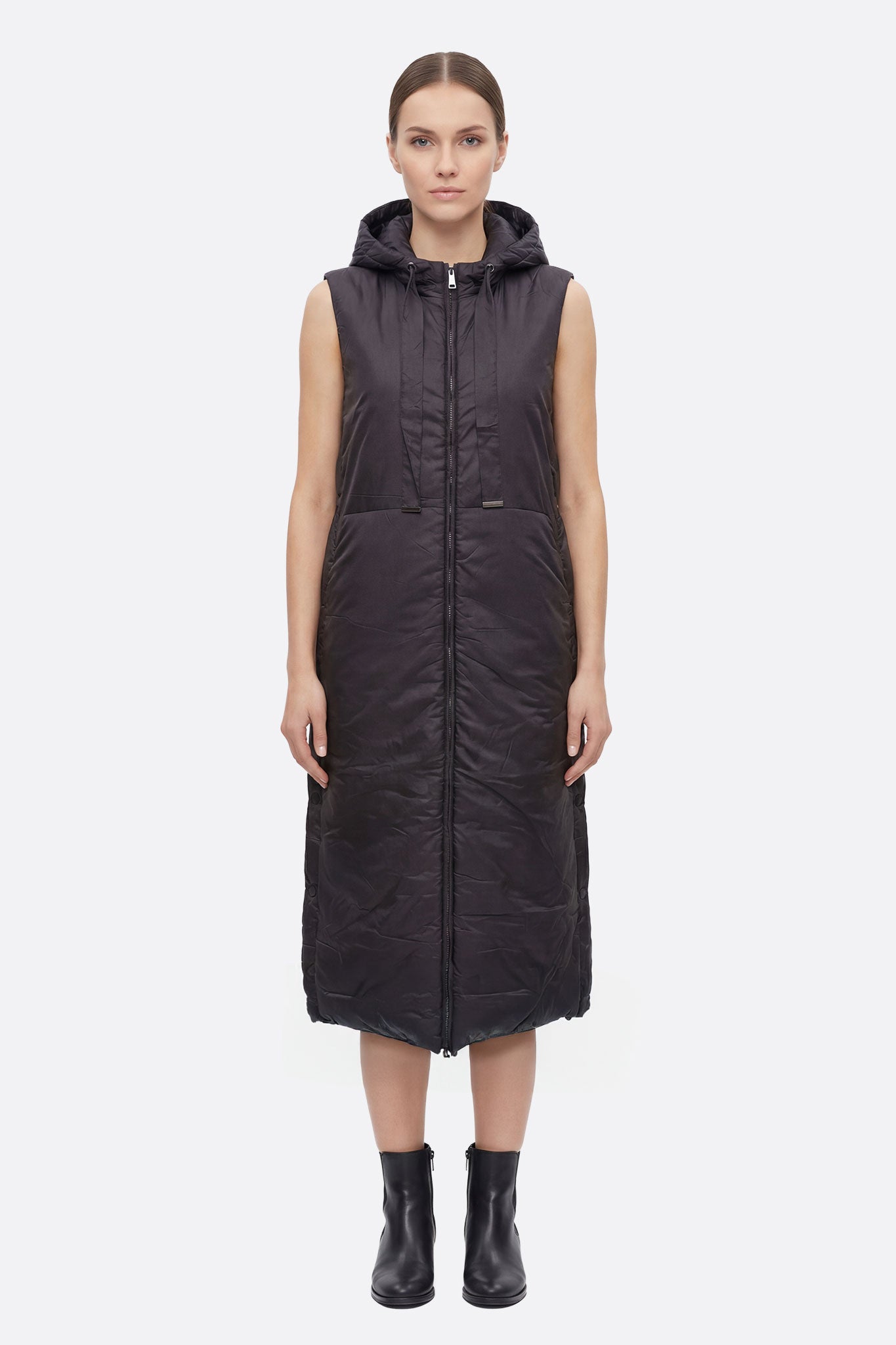 Chaqueta acolchada larga sin mangas negra con capucha, resaltando su diseño moderno y elegante, perfecta para ocasiones...