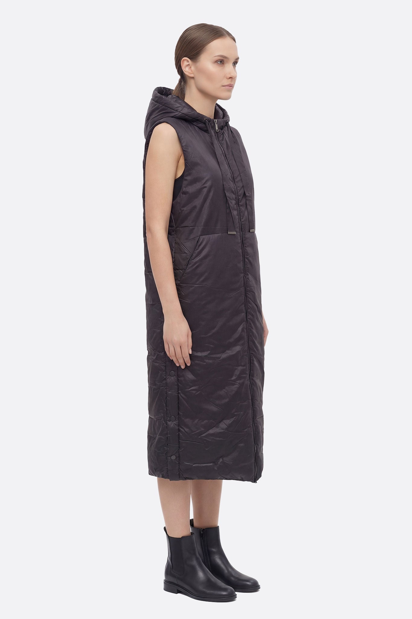 Chaqueta acolchada larga sin mangas negra con capucha, vista lateral que resalta su elegante diseño y comodidad, perfecta...