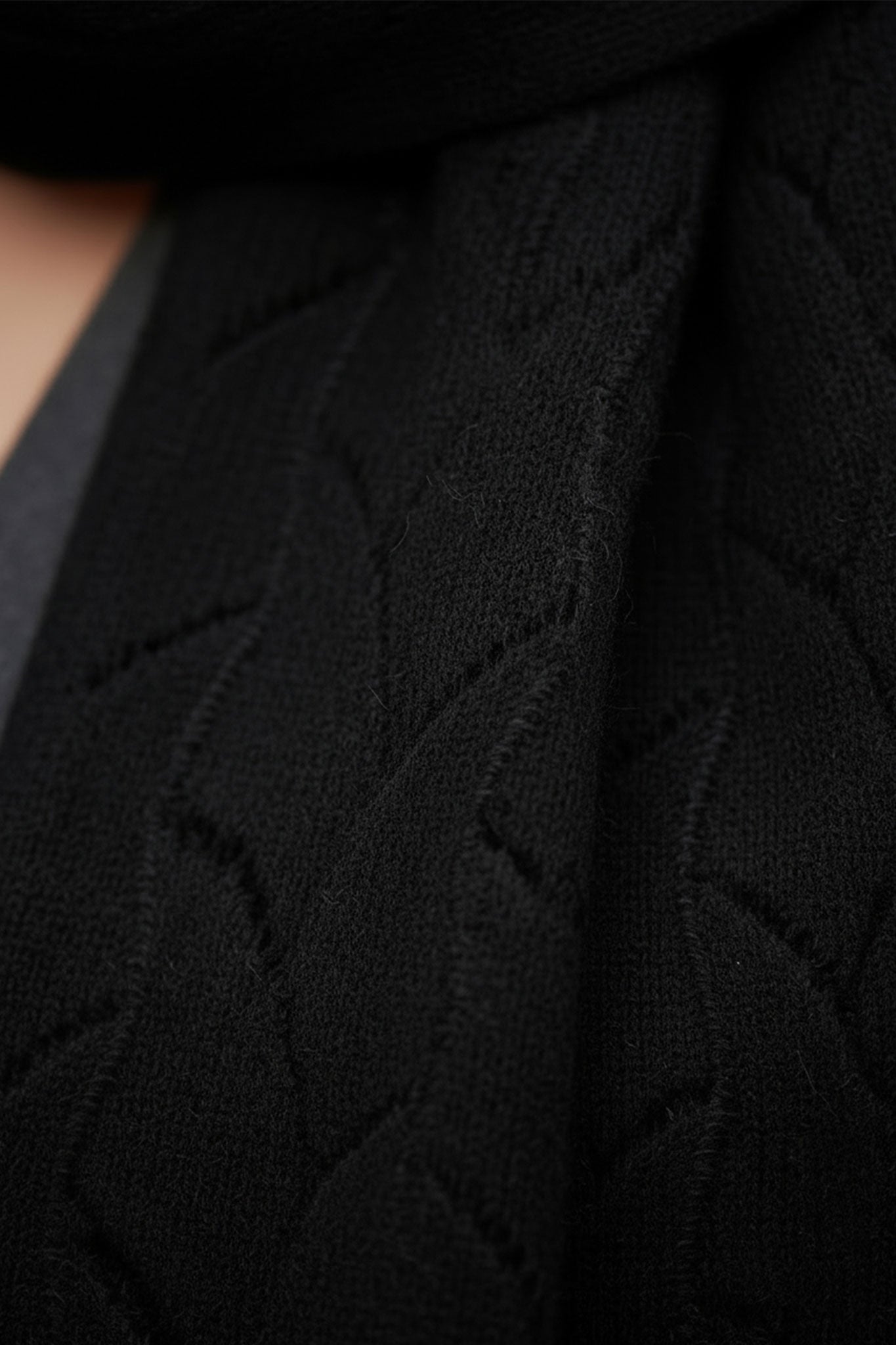 
Détail en gros plan de l'écharpe en cachemire noir à maille ajourée, accessoire chic pour les journées fraîches et élégantes.



