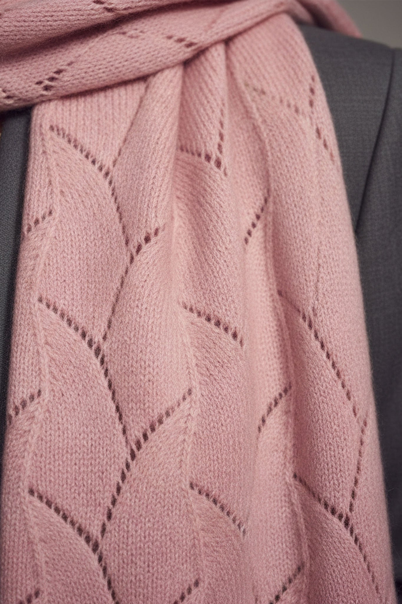 Sciarpa in pregiato cachemire rosa polvere con lavorazione a maglia ajourée, vista 3/4 che evidenzia la sua eleganza e...