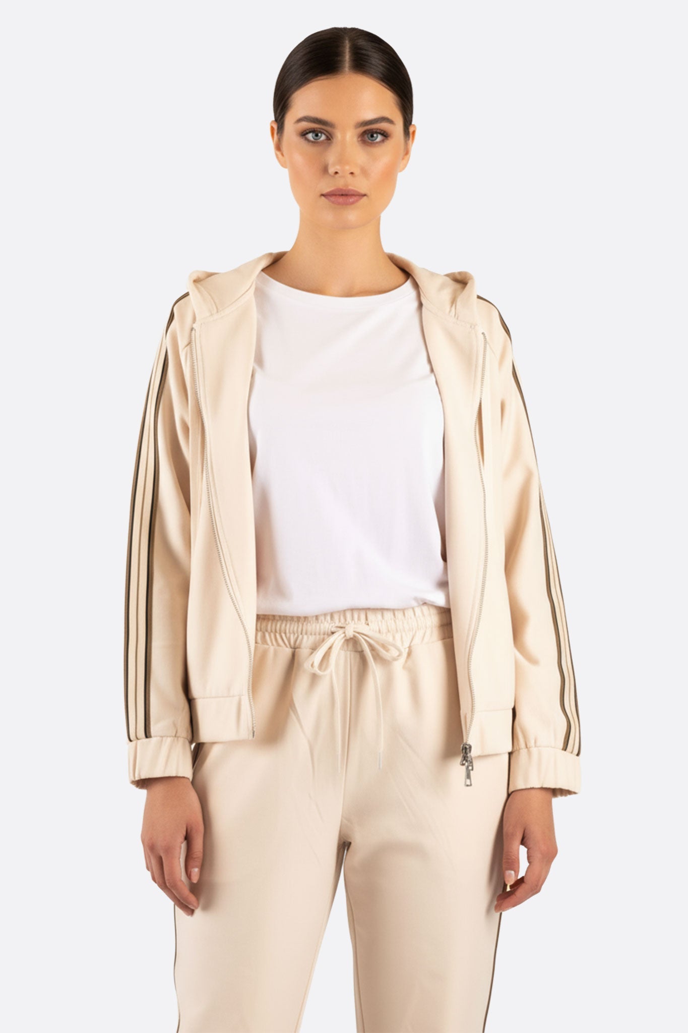 Dettaglio elegante del retro dell'ensemble di jogging beige, evidenziando le bande a contrasto per un tocco chic e...