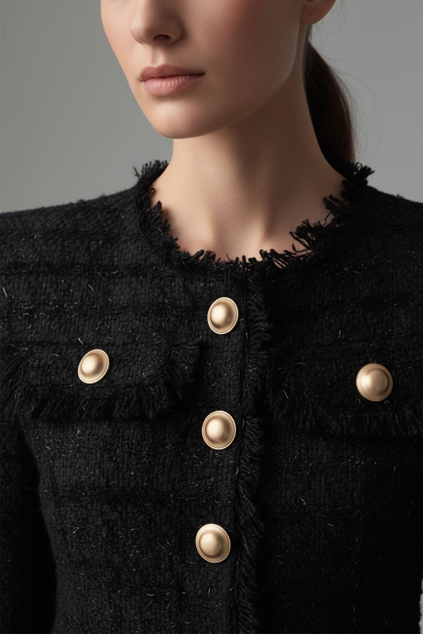 Detalle del botón en tweed negro de la chaqueta de traje femenina, un toque chic para un estilo contemporáneo en eventos...