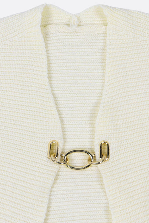 
Détail du cardigan court en maille écrue avec fermeture bijou, une pièce glamour pour un look sophistiqué.



