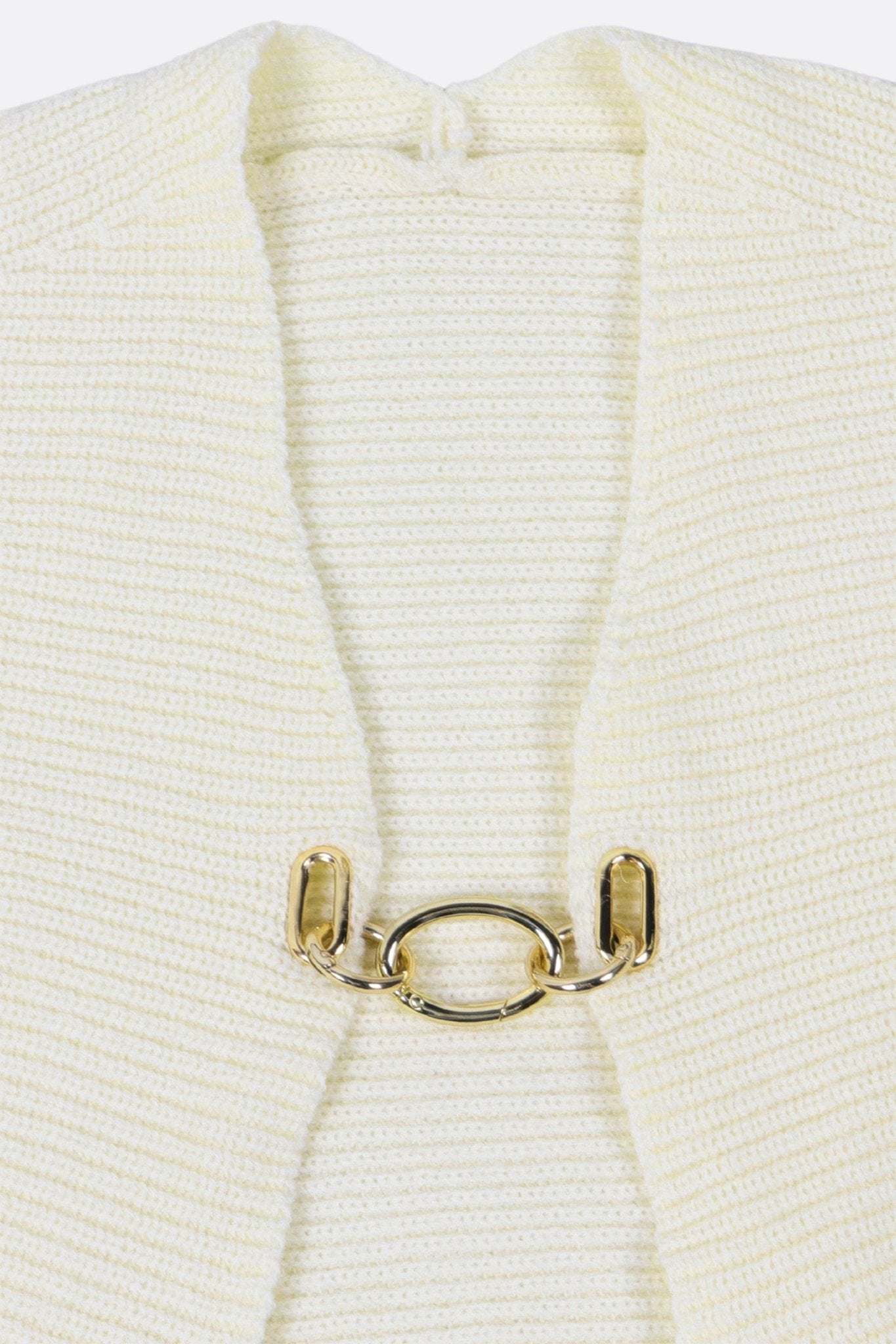 
Détail du cardigan court en maille écrue avec fermeture bijou, une pièce glamour pour un look sophistiqué.



