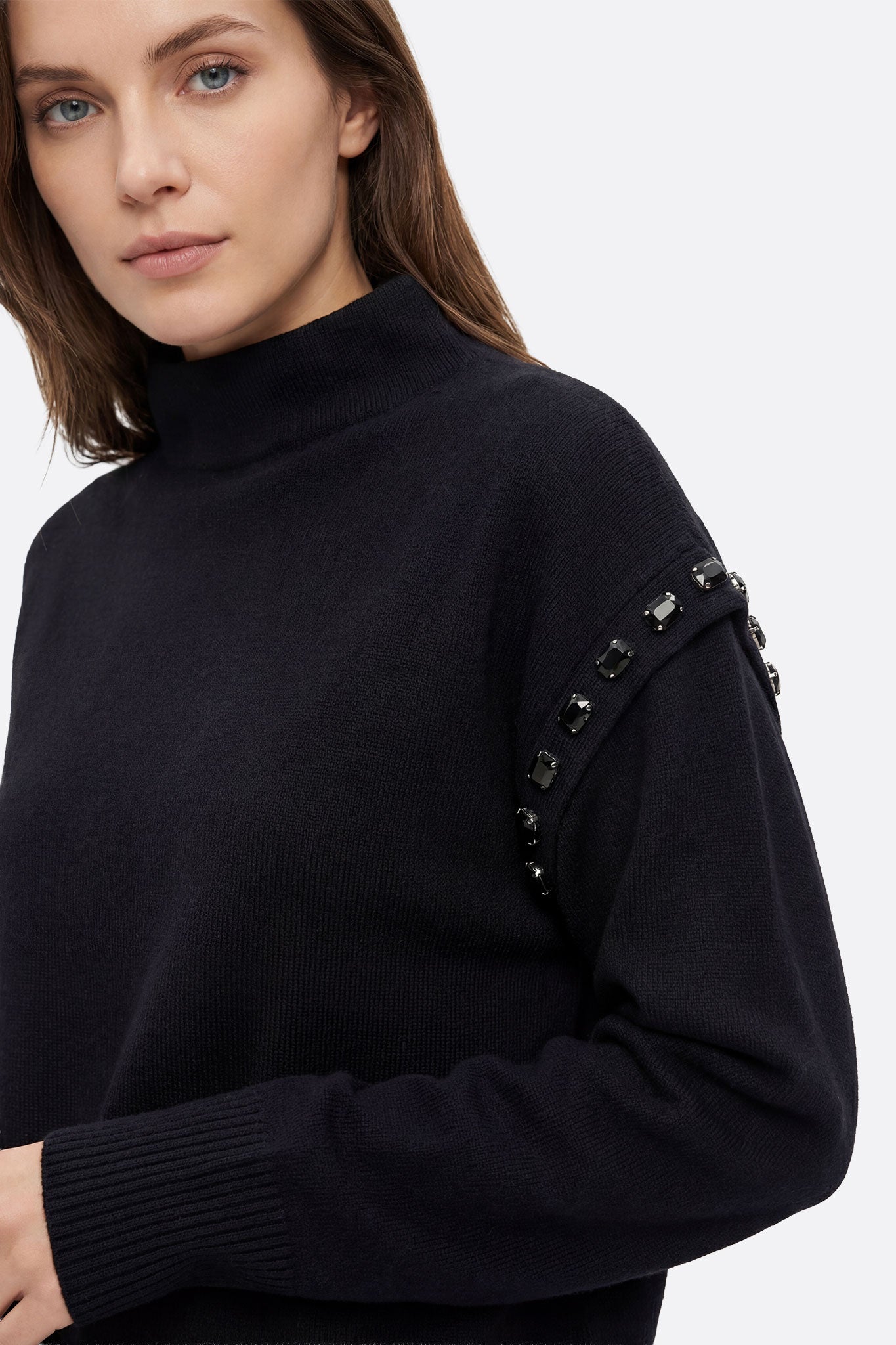 Zoom sur les finitions délicates du pull noir en maille et la jupe longue fluide, ensemble parfait pour une sortie raffinée.