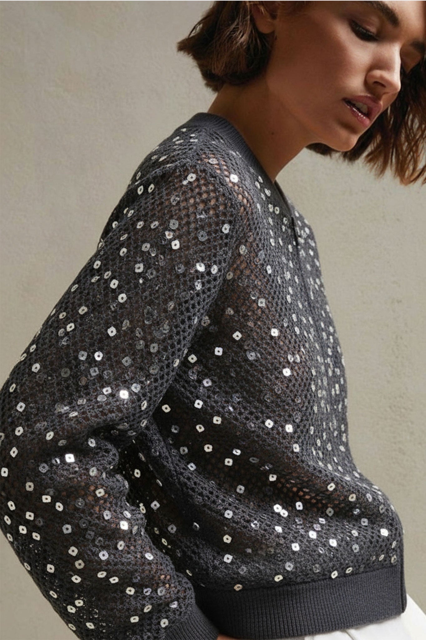 
Détail du gilet gris en lin et coton, ajouré avec sequins scintillants, parfait pour une tenue chic en soirée.



