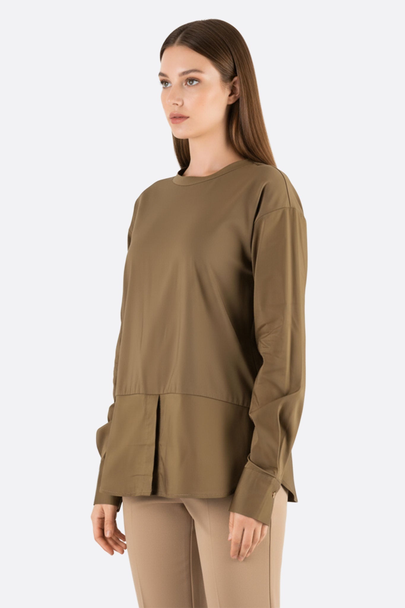 Dettaglio zoomato su un elegante top verde kaki a maniche lunghe, con materiali combinati per un look chic e confortevole.